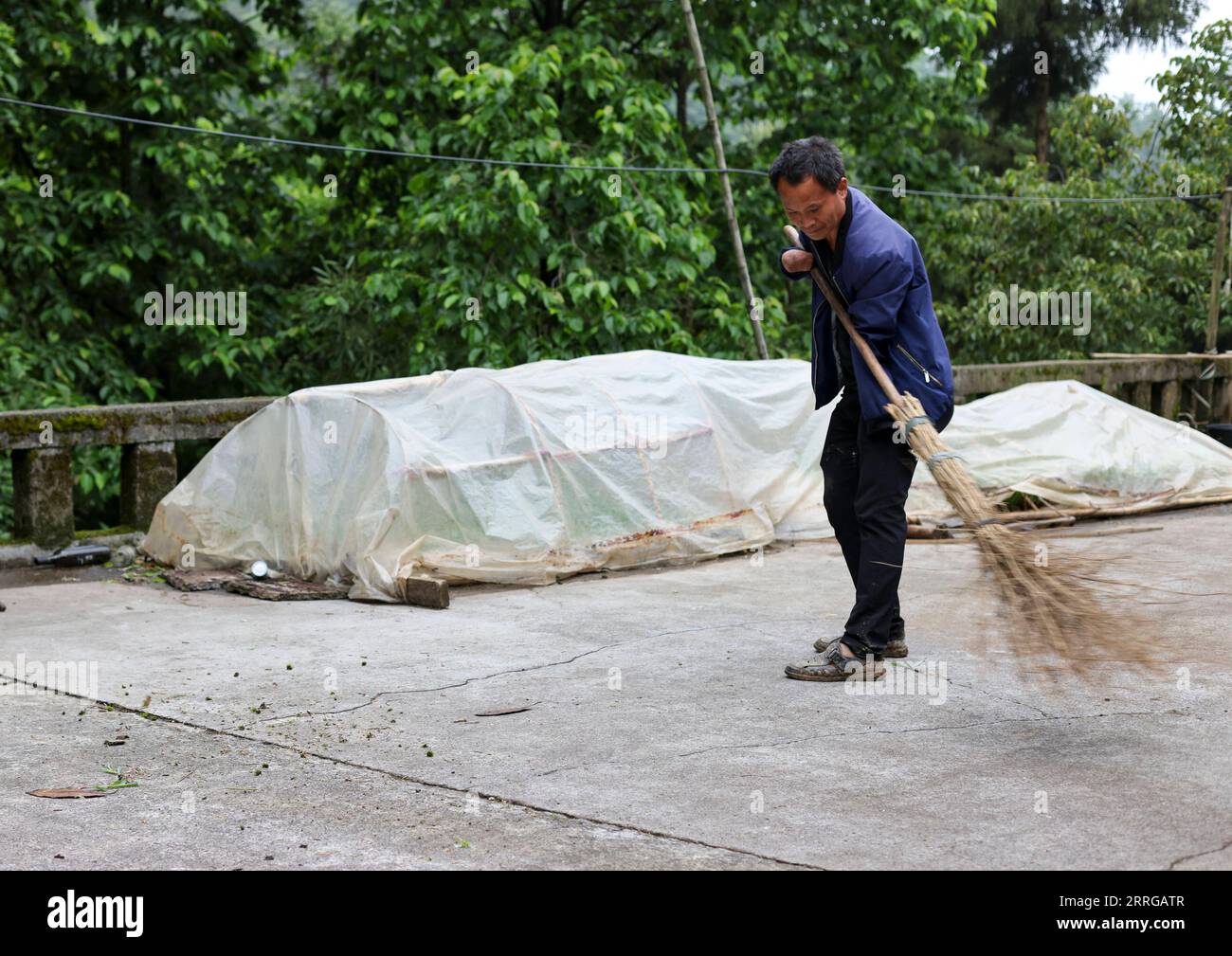 220516 -- ZUNYI, le 16 mai 2022 -- Zhao Youliang nettoie la cour de sa maison dans le canton de Zhongguan, comté de Zheng an, province du Guizhou au sud-ouest de la Chine, le 12 mai 2022. Vivant au cœur des montagnes de Zunyi dans la province du Guizhou, Zhao Youliang et Jian Qin sont un couple handicapé. Zhao, âgé de 50 ans, a perdu ses mains à cause d'une amputation à un jeune âge, et Jian, âgée de 43 ans, a perdu la vue à cause du retard dans le traitement d'une maladie dans son enfance. Dans la vie quotidienne, Zhao aide sa femme à voir avec ses yeux, tandis que Jian aide son mari avec ses mains. Le couple a été suppo Banque D'Images