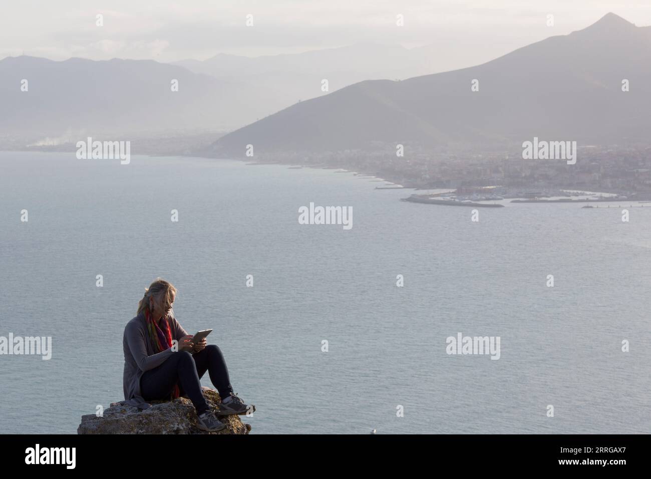 Femme mature assis sur le rocher au-dessus de la mer et des montagnes et des textes Banque D'Images