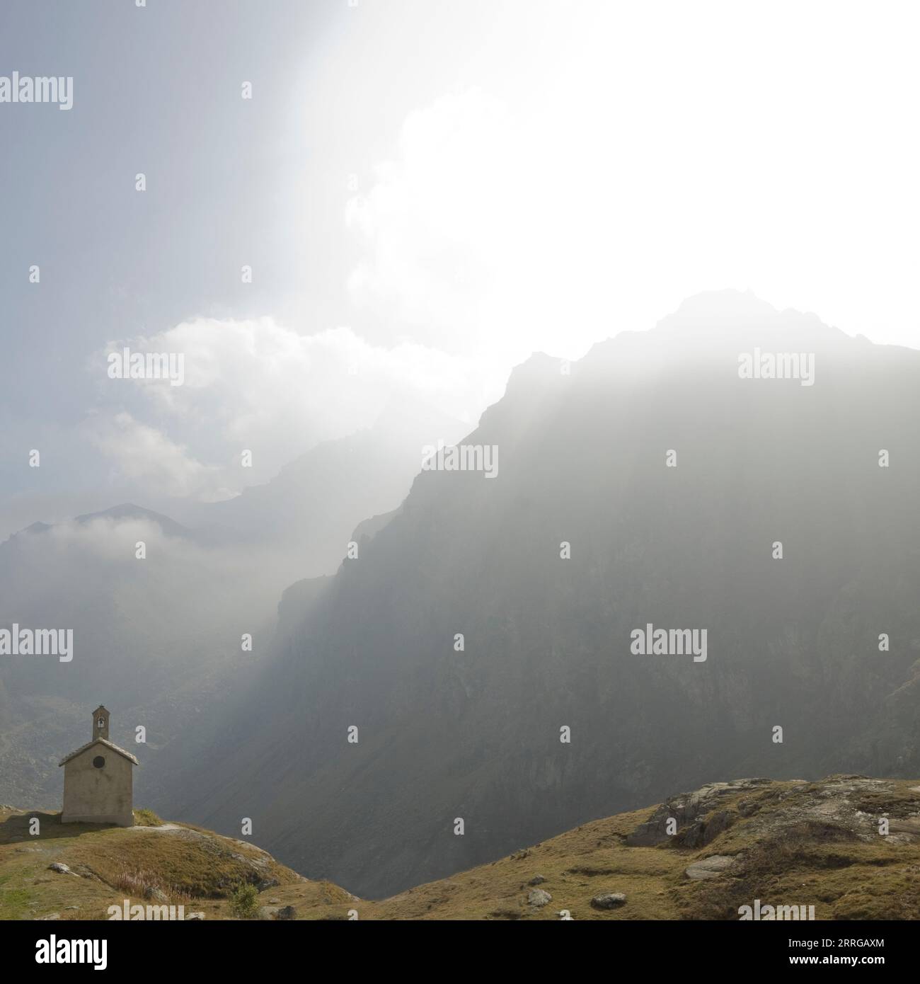Petite église perchée en alpine avec des rayons de soleil Banque D'Images