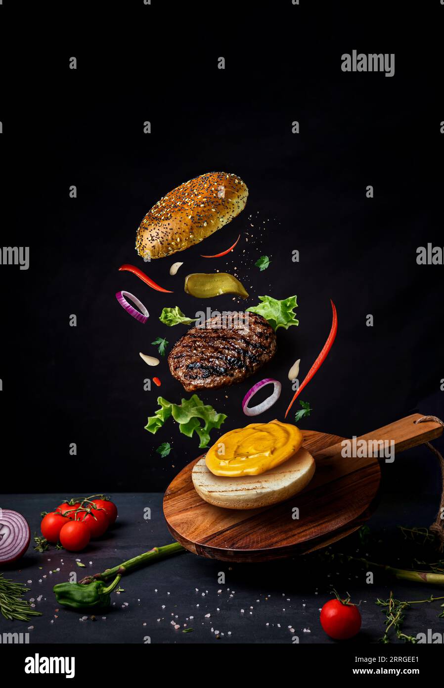 Burger avec des ingrédients volants sur le bois. Photographie culinaire Banque D'Images
