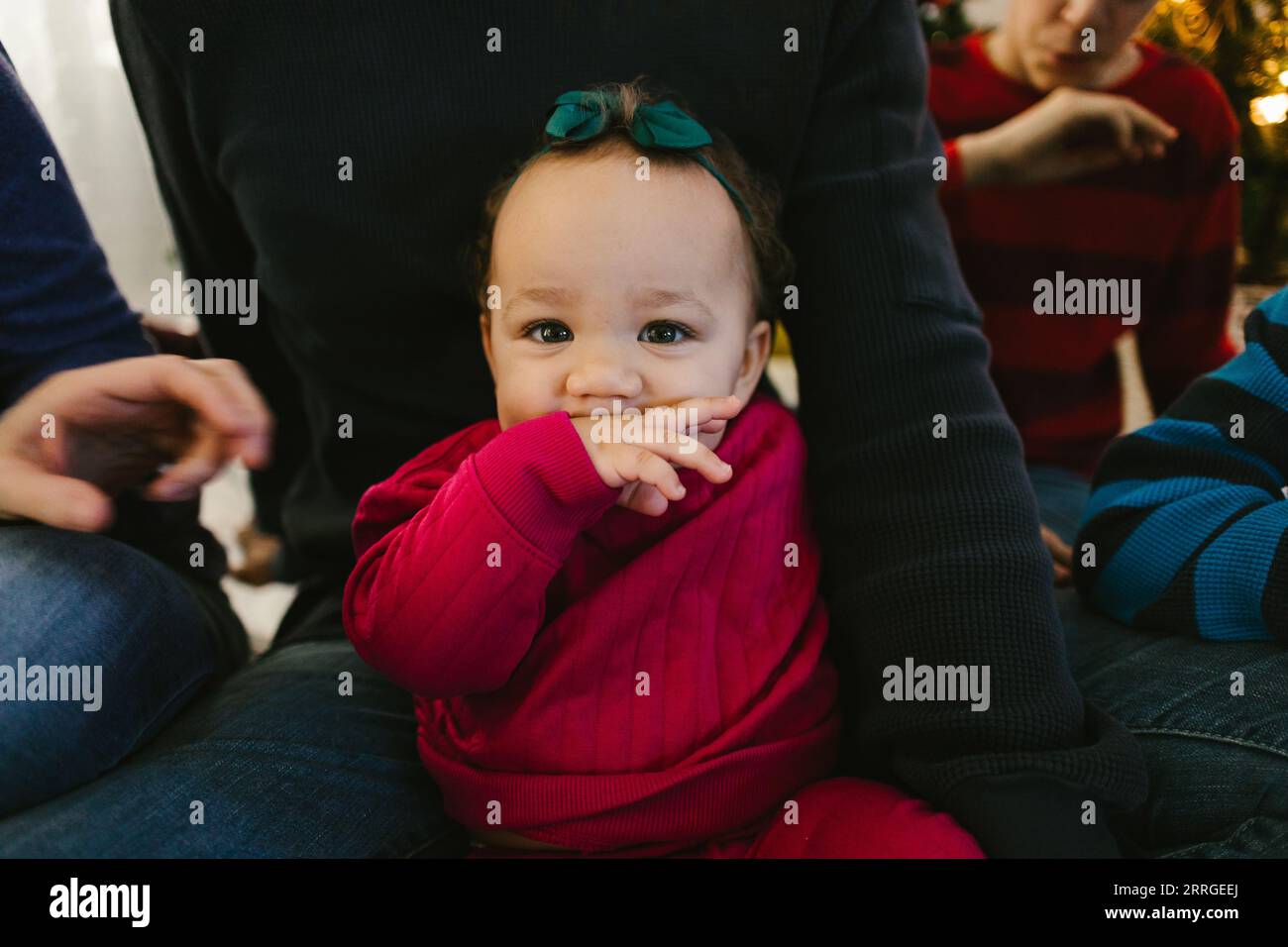 Belle fille multiraciale bébé en tenue rose avec la famille Banque D'Images