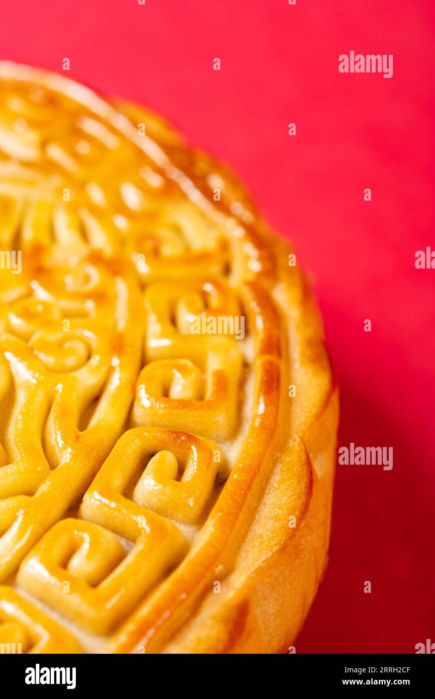 Partie d'un gâteau de lune chinois traditionnel sur rouge avec composition verticale d'espace de copie Banque D'Images