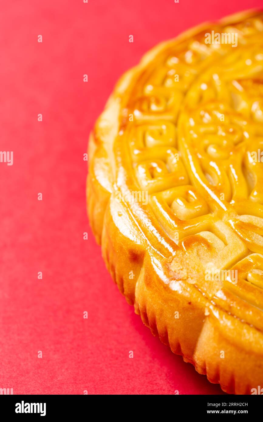 Partie d'un gâteau de lune chinois traditionnel sur rouge avec composition verticale d'espace de copie Banque D'Images