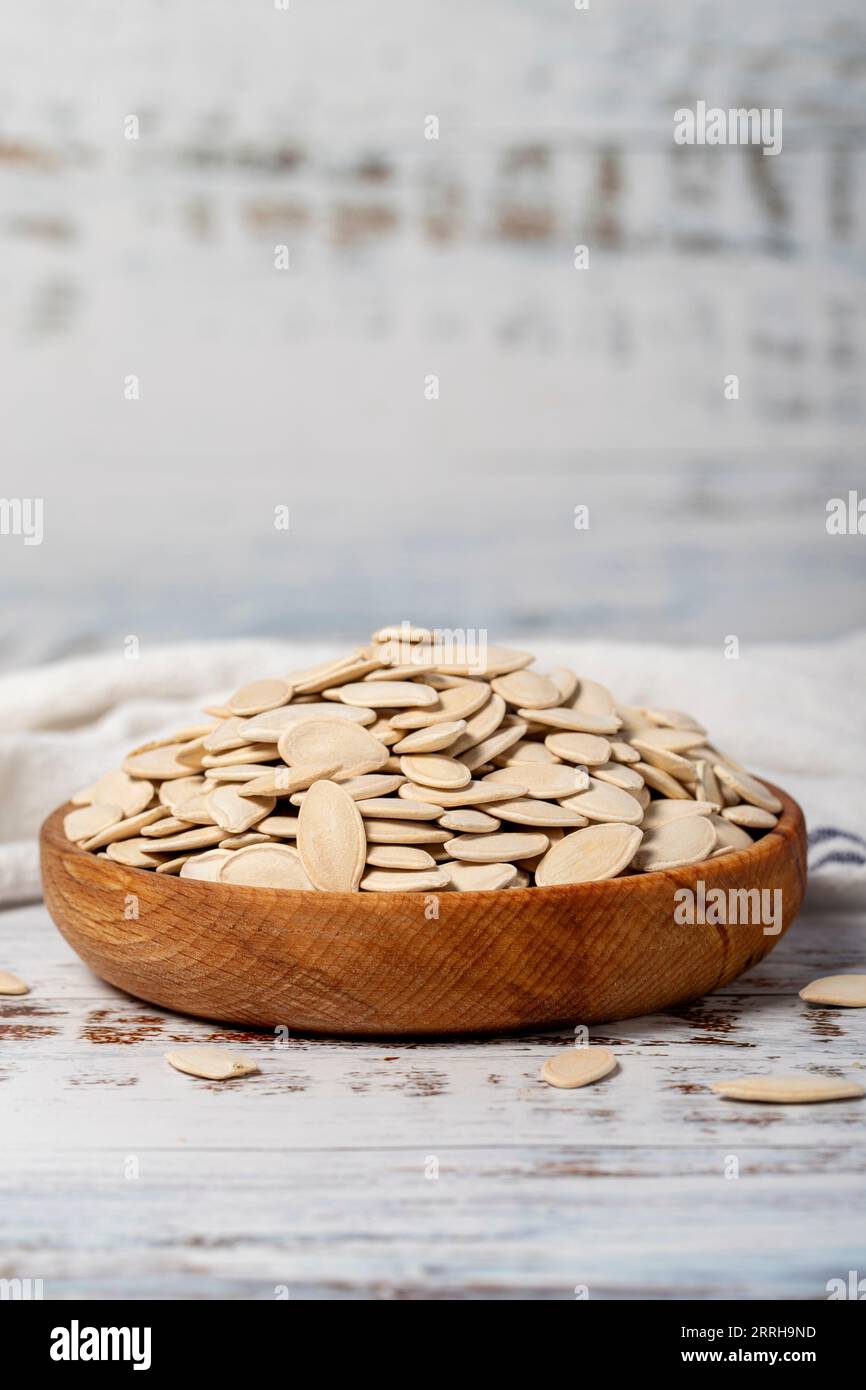 Graines de citrouille dans un bol en bois. Graines de citrouille décortiquées sur un fond de bois blanc Banque D'Images