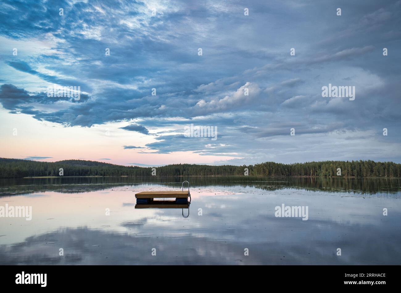 Île de baignade en Suède sur un lac au coucher du soleil. Nuages réfléchis dans l'eau. Natation plaisir en vacances avec loisirs en Scandinavie Banque D'Images