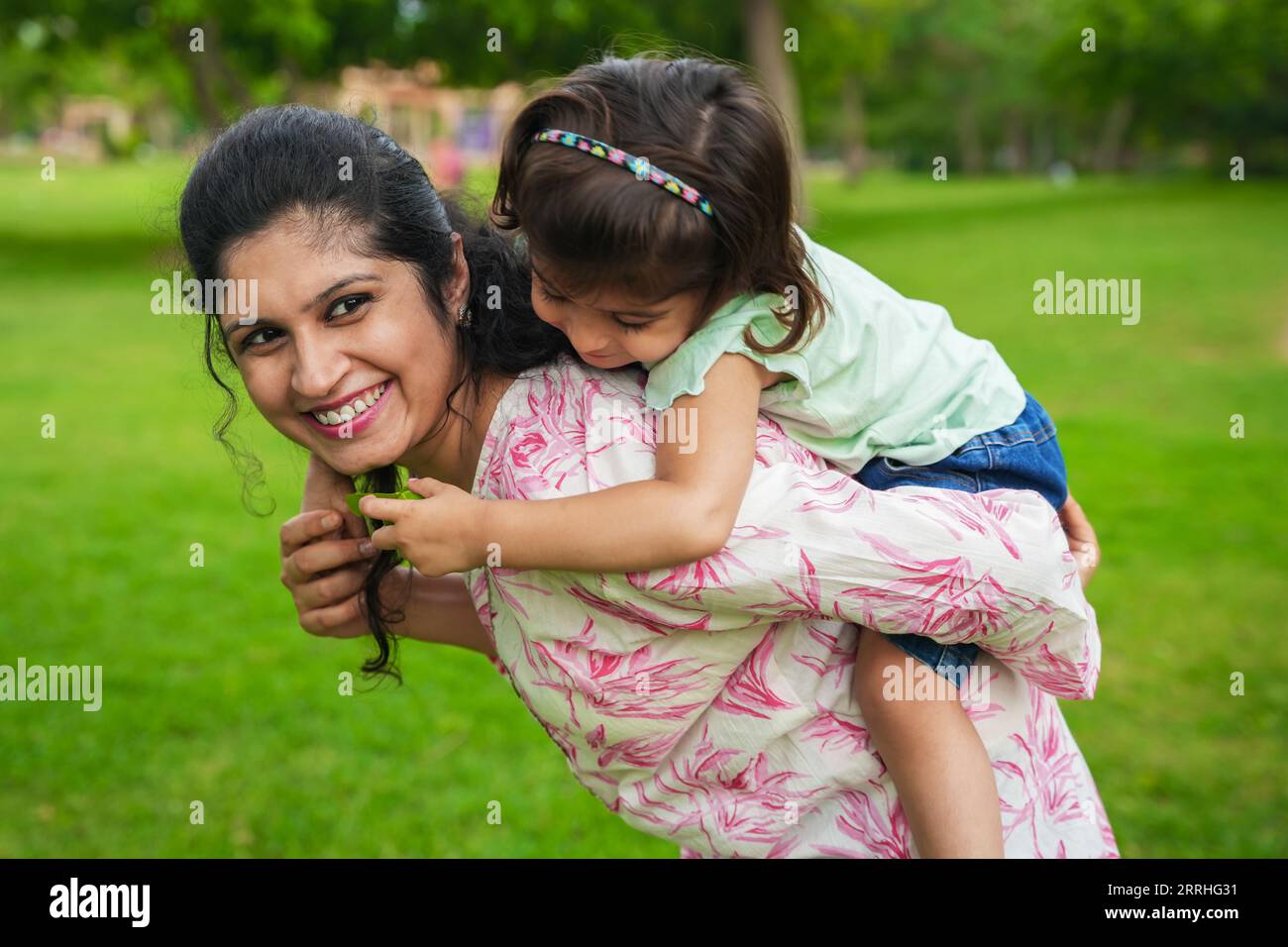 Heureuse jeune fille indienne enfant jouant cochon dos ride avec sa mère au parc d'été concept de famille et de maternité. Banque D'Images