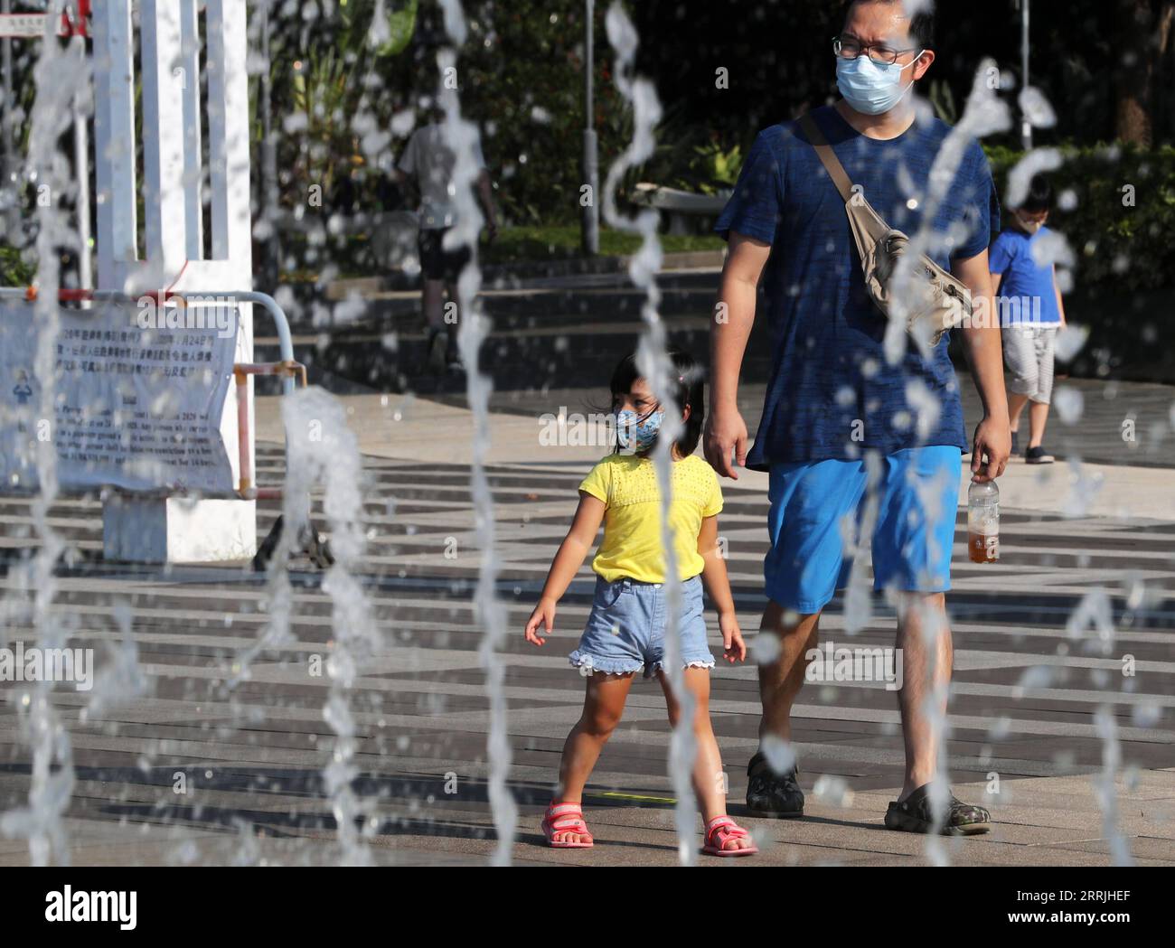 220724 -- HONG KONG, le 24 juillet 2022 -- les gens passent devant une fontaine par une chaude journée d'été dans le sud de la Chine Hong Kong, le 24 juillet 2022. CHINE-HONG KONG-TEMPS CHAUD CN LIXGANG PUBLICATIONXNOTXINXCHN Banque D'Images