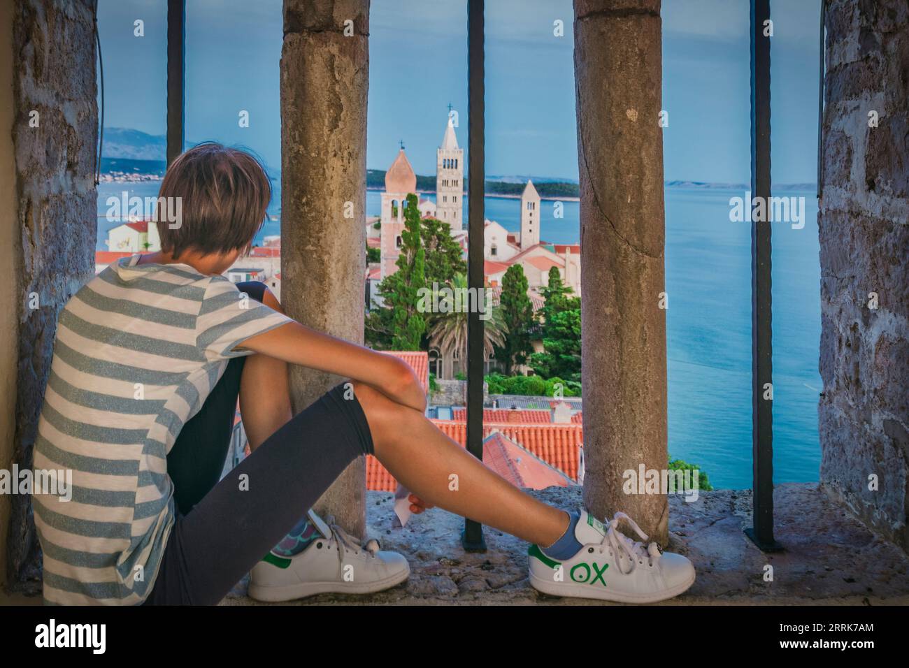 Europe, Croatie, comté de Primorje-Gorski Kotar, île de Rab, jeune fille (14 ans) regarde vers le bas sur la vieille ville de Rab au crépuscule Banque D'Images