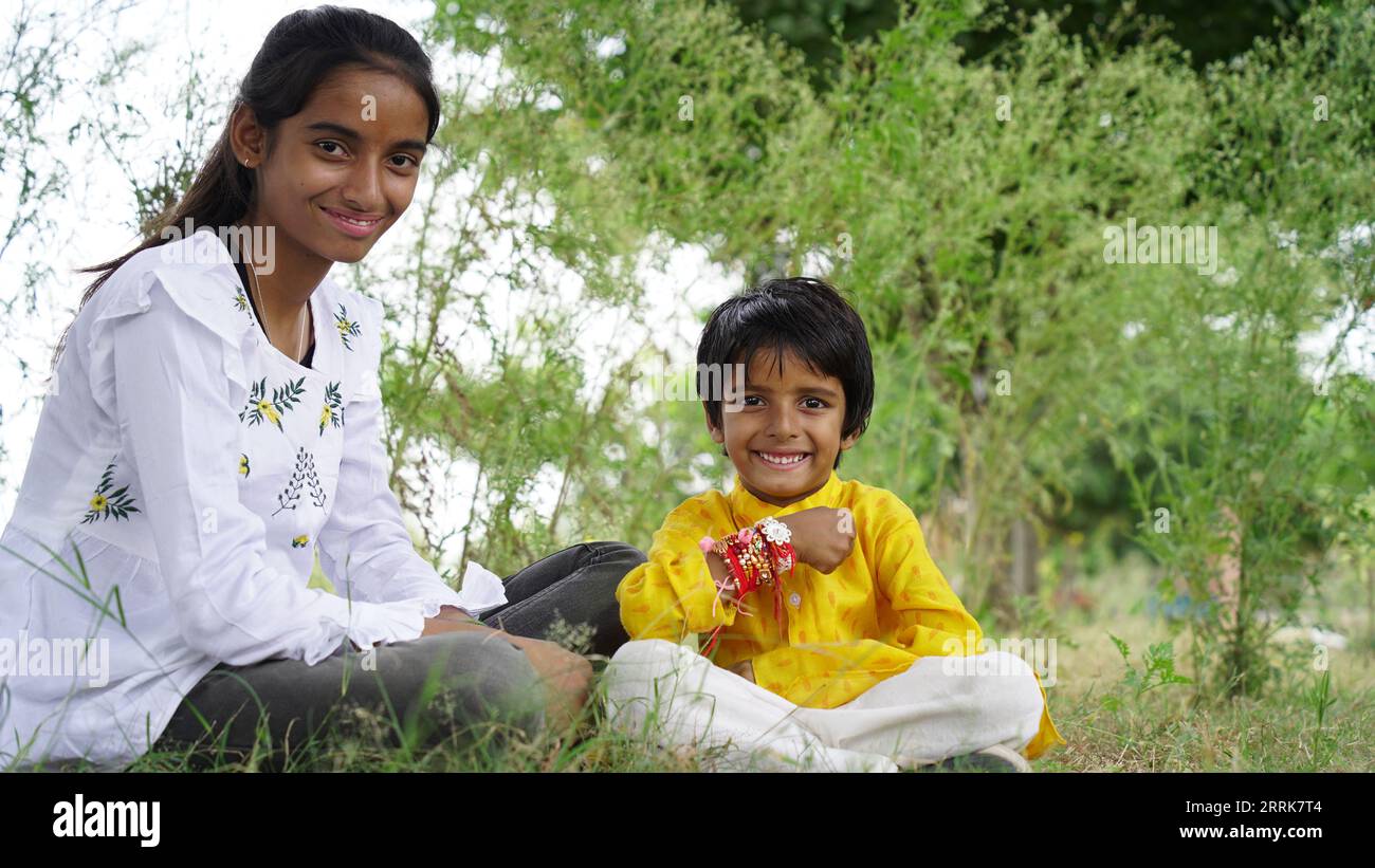 Frère et sœur hindous en vêtements ethniques tenant des bonbons indiens et boîte cadeau à l'occasion du festival Raksha Bandhan Banque D'Images