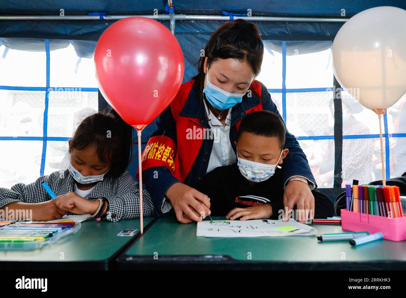 220910 -- LUDING, 10 septembre 2022 -- Sun Yan C, volontaire, dessine des photos avec des enfants dans une salle de classe sous tente au refuge de secours contre les tremblements de terre de l'école secondaire Luding n° 2 à Luding, dans la province du Sichuan, dans le sud-ouest de la Chine, le 10 septembre 2022. Après un tremblement de terre de magnitude 6,8 qui a secoué lundi le comté de Luding, dans la province du Sichuan, dans le sud-ouest de la Chine, plus de 800 villageois de la ville de Detuo, dont environ 50 enfants, ont été temporairement relocalisés au lycée n°2 de Luding. Depuis le 6 septembre, 11 enseignants des jardins d enfants de Luding et 10 élèves des collèges et lycées se sont portés volontaires pour s occuper de ces enfants. Banque D'Images