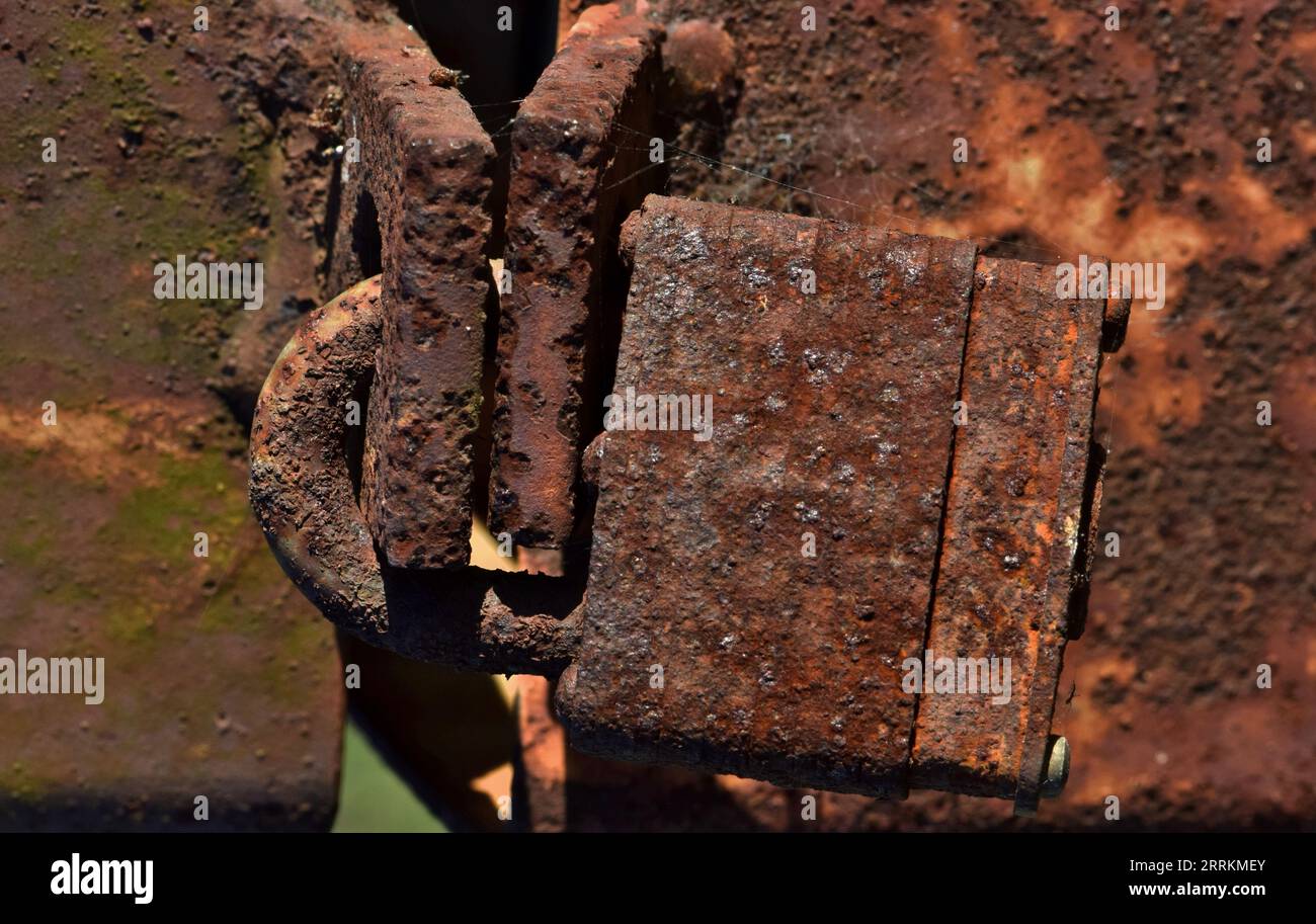 Serrure rouillée sur un poteau métallique rouillé. Cadenas corrodé à gros plan isolé, image détaillée du processus de corrosion de l'oxyde de fer. Banque D'Images