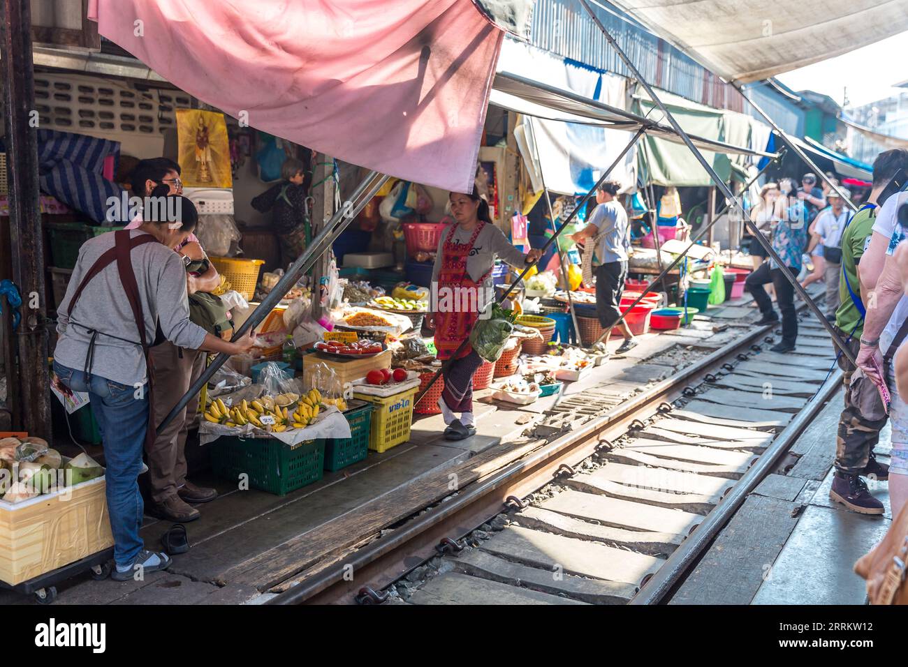 Les vendeurs déplacent leurs marchandises et rattrapent les auvents quand un train arrive, vendant de la nourriture sur les rails, le marché du chemin de fer Maeklong, le marché du chemin de fer Talad ROM Hub, près de Bangkok, Samut Songkhram, Thaïlande, Asie Banque D'Images