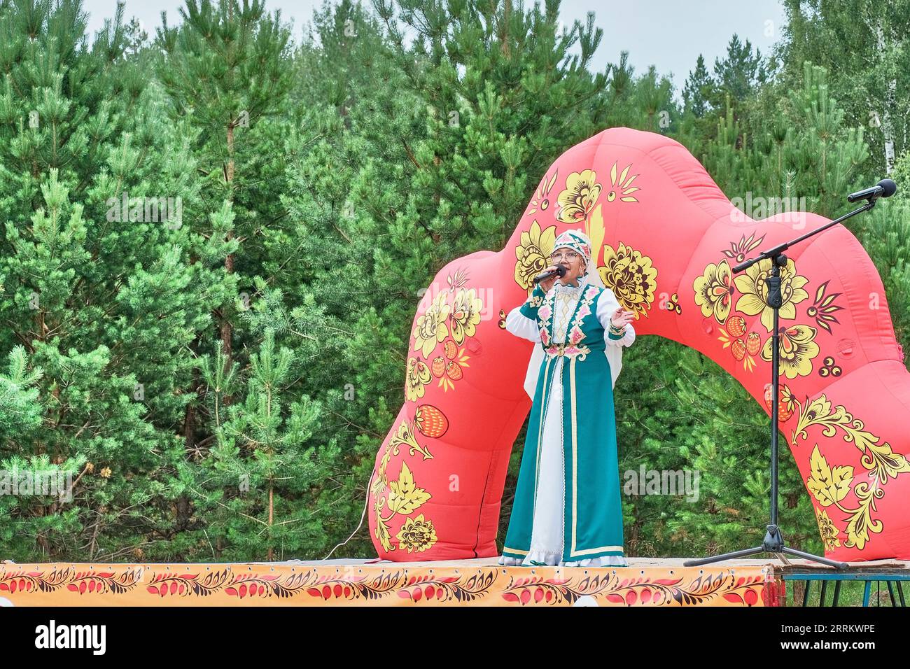 Femme asiatique mature dans des vêtements stylisés de Tatars ethniques, se produisant sur scène. Fête du village. Jour de la petite patrie, Sibérie, Russie Banque D'Images