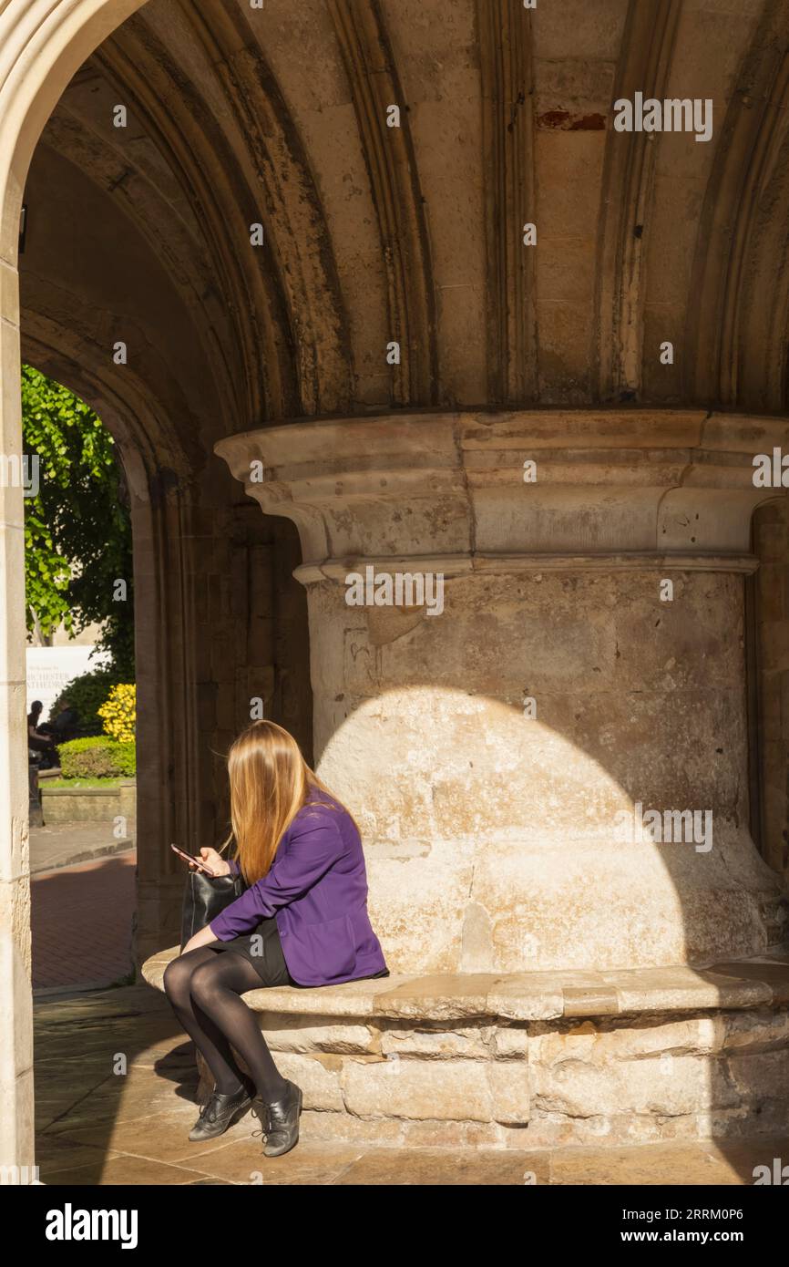 Angleterre, Sussex, West Sussex, Chichester, Chichester Market Cross, Fille d'école assise sous Market Cross avec téléphone portable Banque D'Images