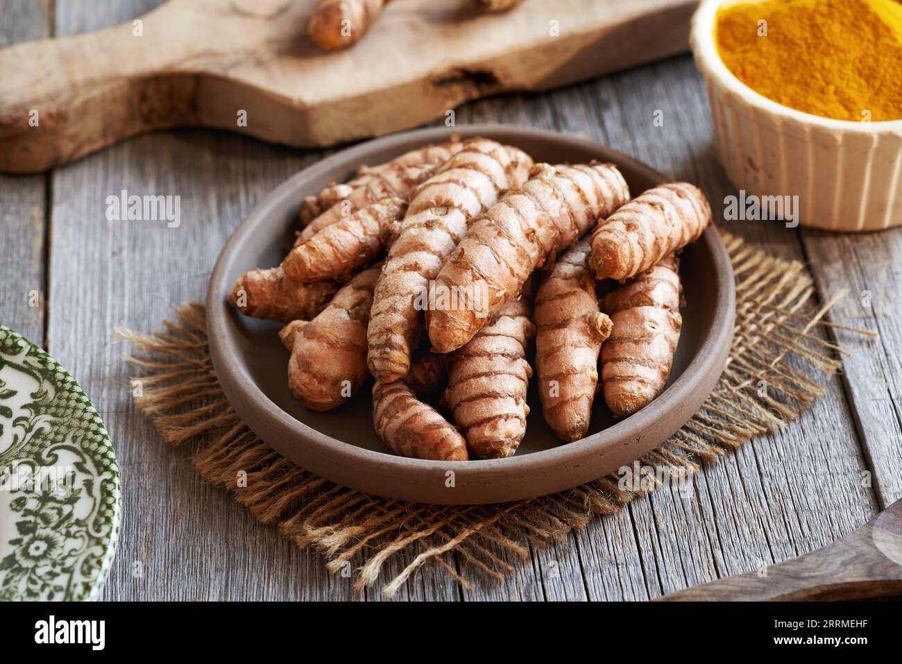 Racine de curcuma crue sur une table en bois avec de la poudre de curcuma sèche en arrière-plan Banque D'Images