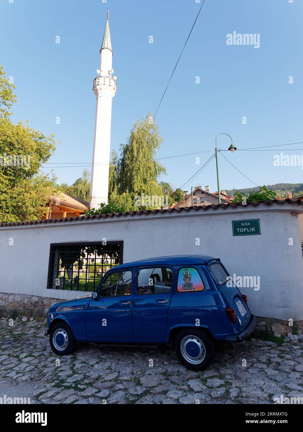 Petite voiture bleue garée dans une rue pavée avec minaret derrière dans la ville de Sarajevo, Bosnie-Herzégovine, 08 septembre 2023 Banque D'Images