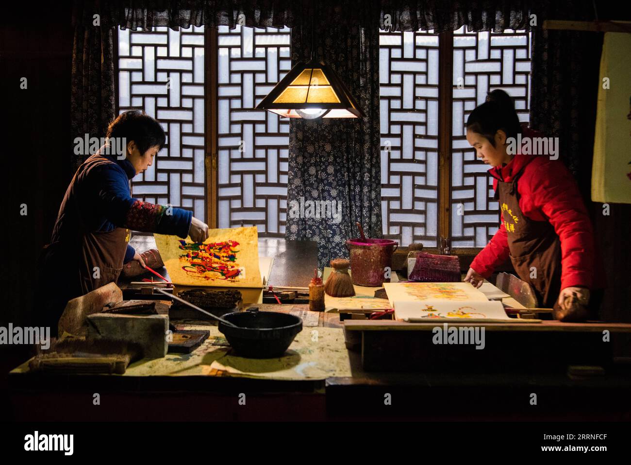 230109 -- PÉKIN, le 9 janvier 2023 -- l'artiste Yin Dongxiang L et sa fille Xiao Yang font des copies de nianhua, un type d'image du nouvel an gravé sur bois chinois vieux de plusieurs siècles, dans un atelier du canton de Tantou, dans le comté de Longhui, Shaoyang, province du Hunan en Chine centrale, le 21 janvier 2022. XINHUA-PHOTOS DE L'ANNÉE 2022-CHINE NOUVELLES CHENXSIHAN PUBLICATIONXNOTXINXCHN Banque D'Images