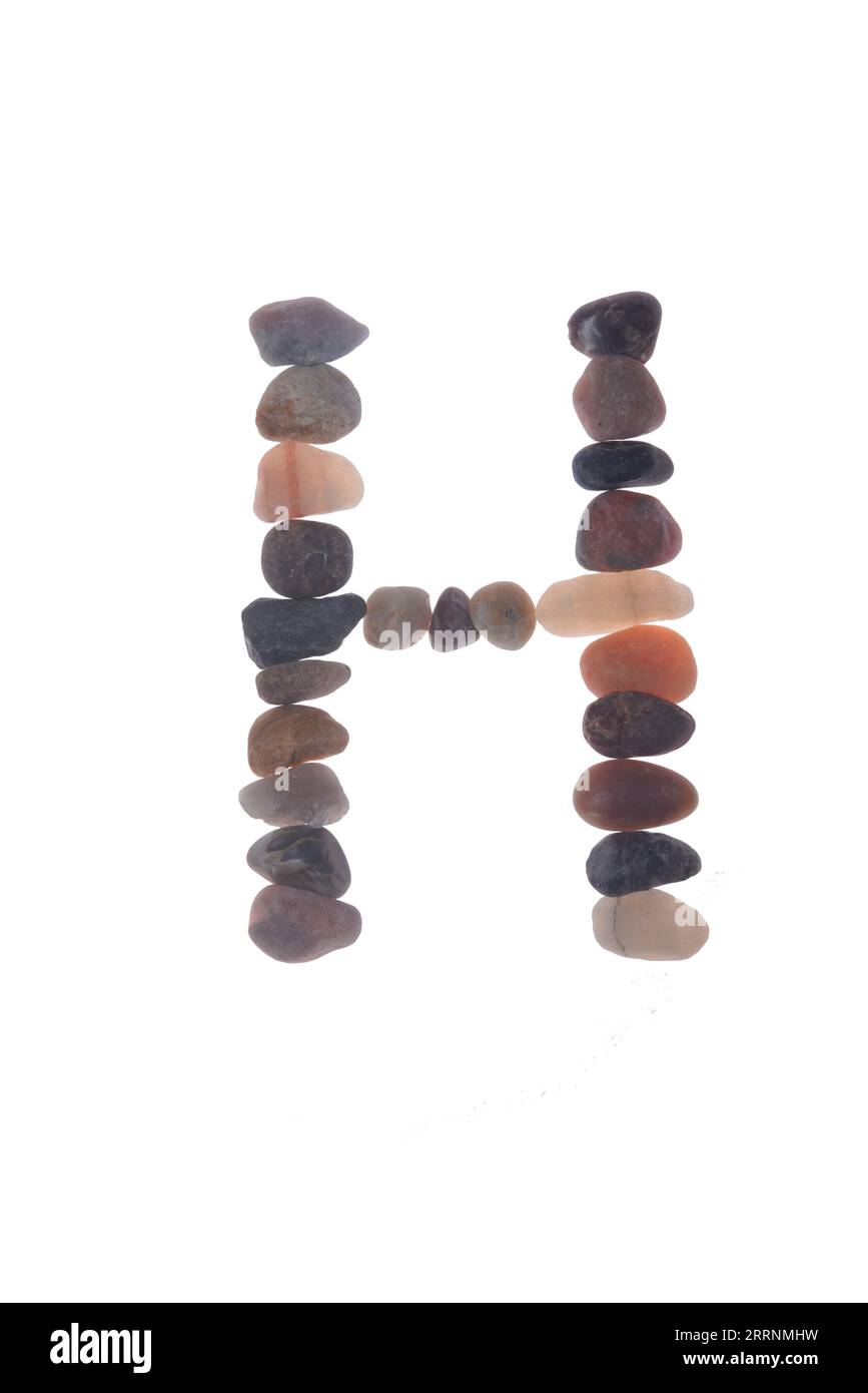 Lettre H fabriquée à la main à l'aide de petites pierres ou cailloux, objet unique. créer un impact artistique signifiant à votre message, sur fond blanc. Banque D'Images