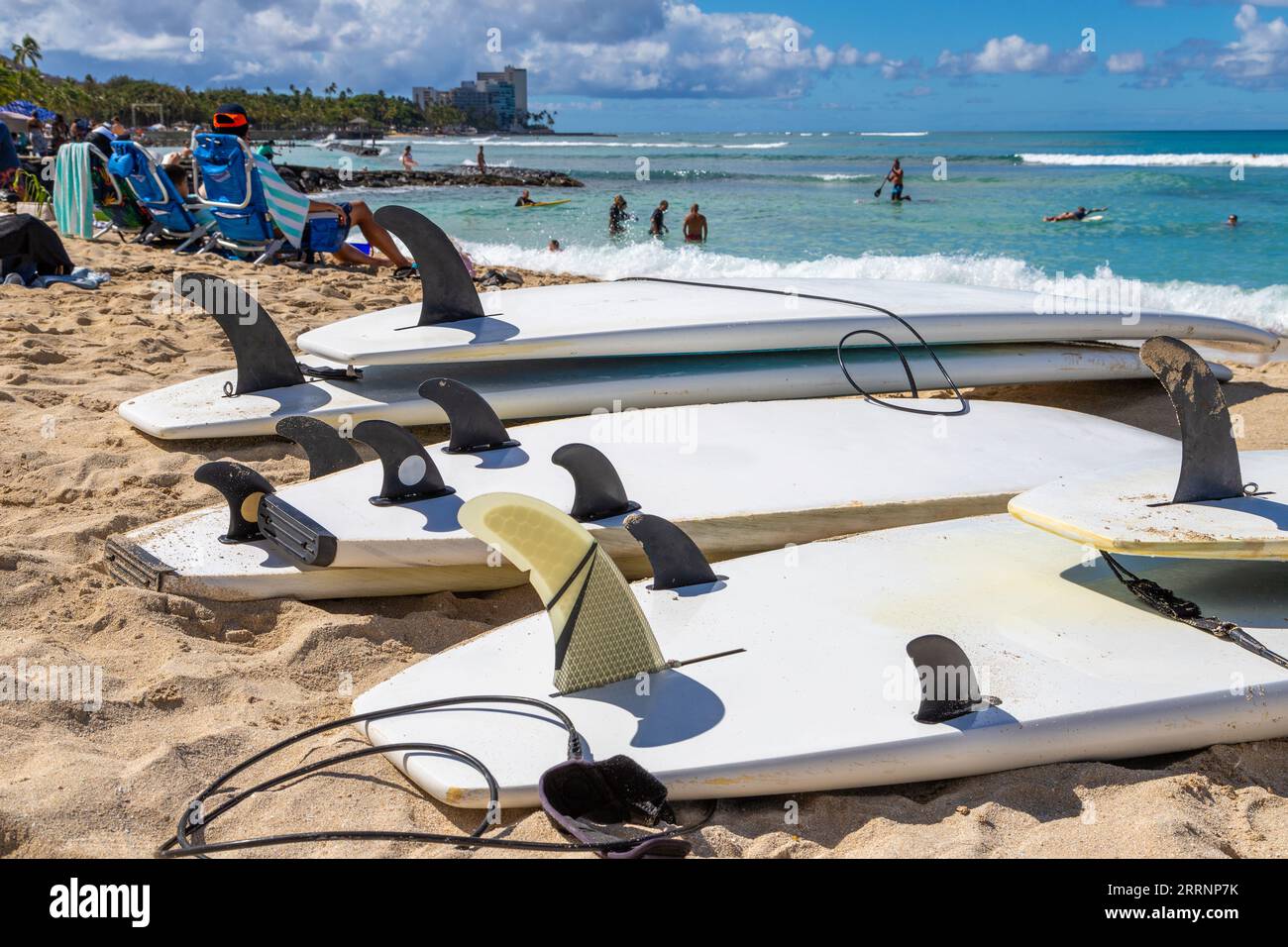 Planches de surf montrant des palmes et des sangles de cheville de laisse couchées sur le sable à Waikiki Beach à Honolulu Hawaii. Arrière-plan flou. Banque D'Images
