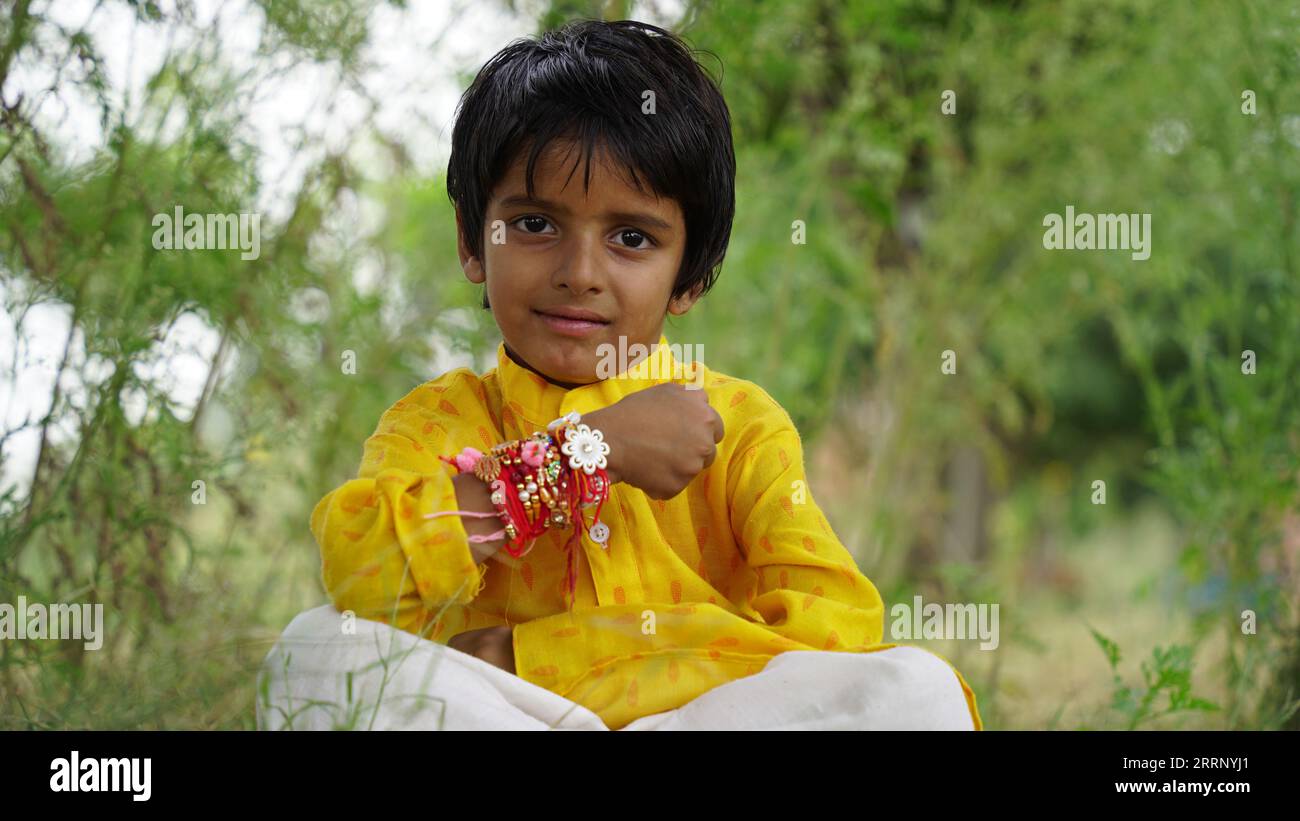 Frère et sœur hindous en vêtements ethniques tenant des bonbons indiens et boîte cadeau à l'occasion du festival Raksha Bandhan Banque D'Images