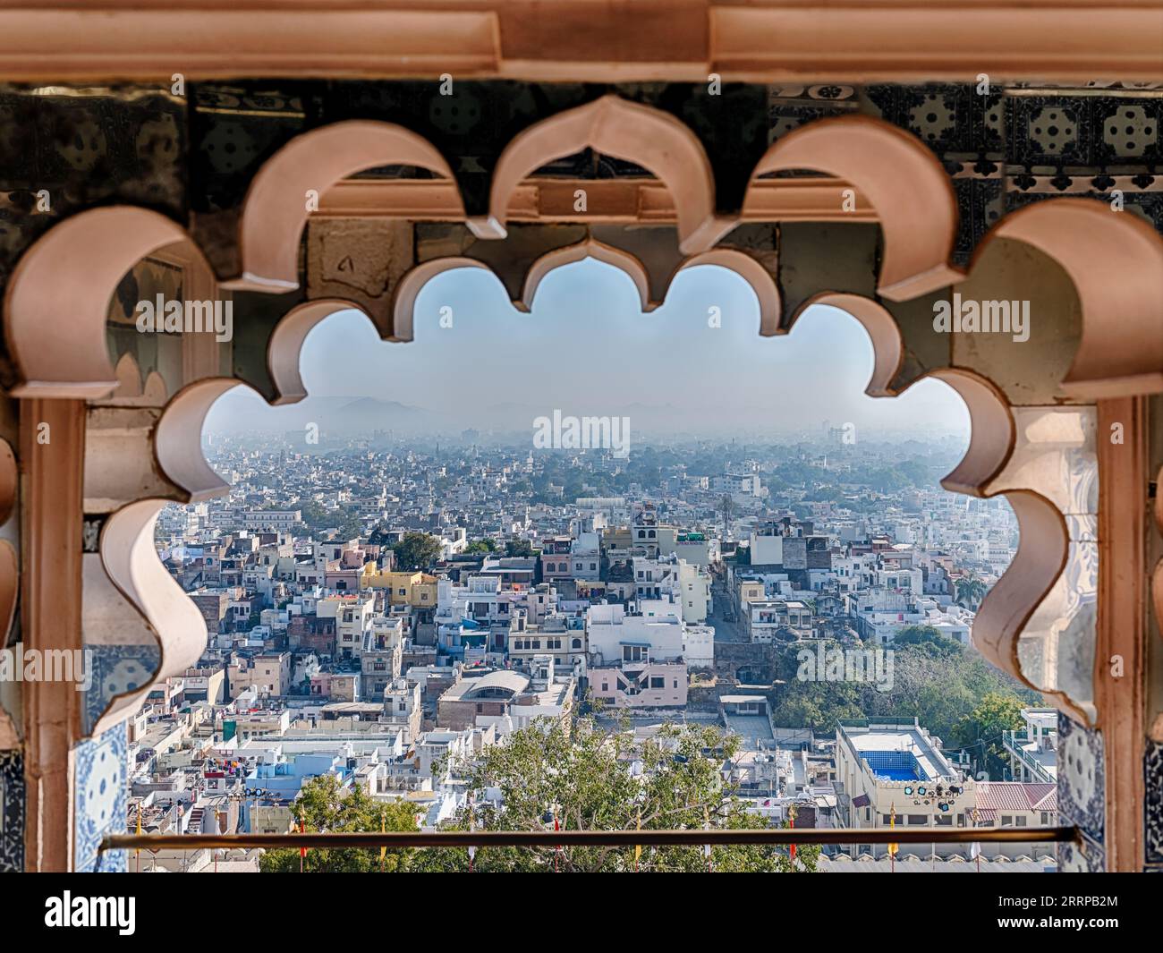 Une vue d'Udaipur à travers un style traditionnel de fenêtre moghol dans le Palais de la ville. Banque D'Images
