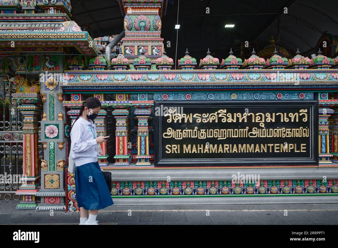 Une écolière thaïlandaise passe devant le temple Sri Mahamariammam (hindou) de style tamoul sur Silom Road, Bangkok Thaïlande Banque D'Images