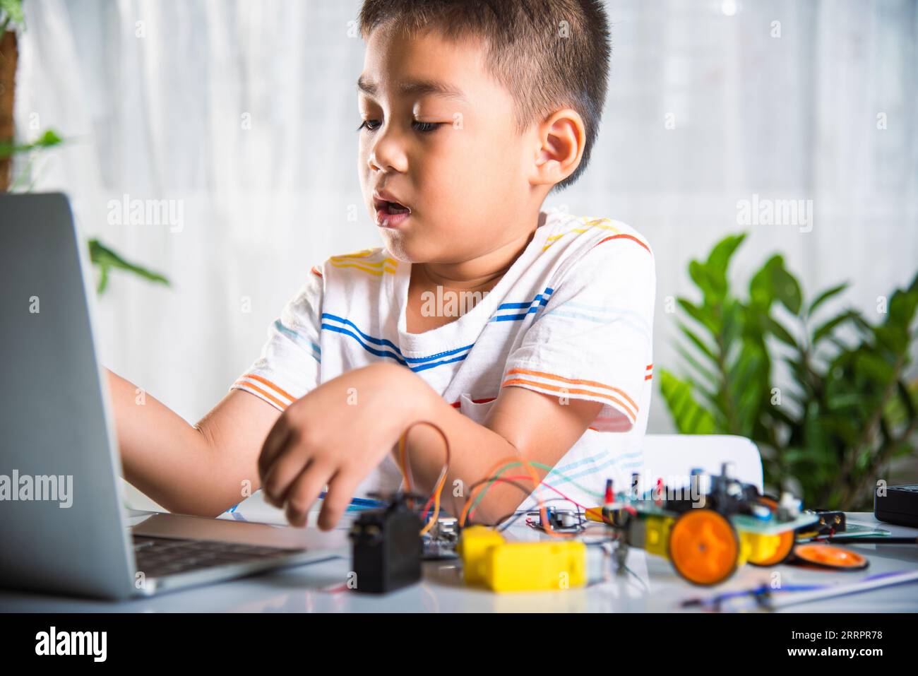 Un enfant asiatique apprend le codage et la programmation avec un ordinateur portable pour la voiture robot Arduino Banque D'Images