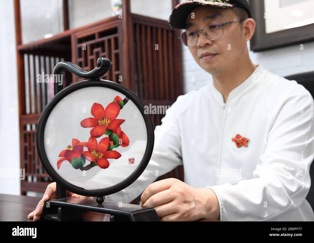 230418 -- GUANGZHOU, 18 avril 2023 -- Wang Xinyuan présente un morceau d'illustration de broderie de Guangzhou sur des fleurs de coton de soie à son atelier dans le district de Liwan de Guangzhou, province du Guangdong dans le sud de la Chine, le 4 avril 2023. La broderie cantonaise est l'une des quatre broderies célèbres en Chine. La broderie de Guangzhou, qui fait partie de la broderie cantonaise, remonte à la dynastie Tang de 618-907 et a une histoire de plus de 1 000 ans. Bénéficiant de plus de 30 types de points de suture, la broderie de Guangzhou est bien connue pour la composition compliquée, l'image vive, la couleur riche et le lustre, et des styles variés. En mai 2006, Banque D'Images