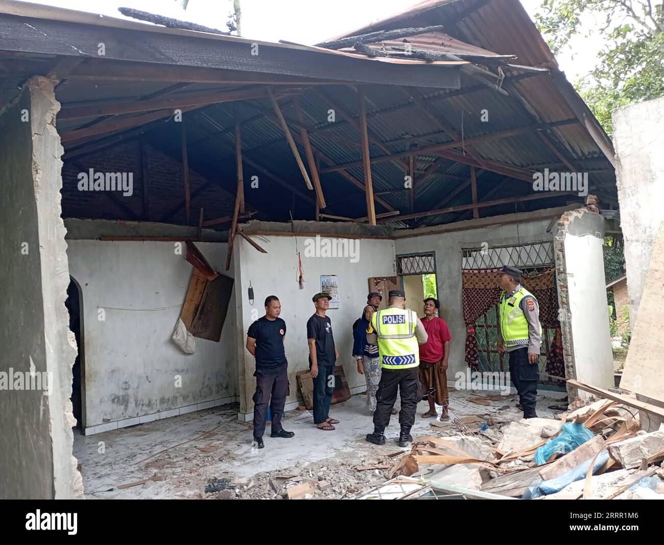 230425 -- MENTAWAI, le 25 avril 2023 -- cette photo prise avec un téléphone portable fourni par l'Agence nationale indonésienne de gestion des catastrophes montre des policiers et des villageois se tenant près d'une maison endommagée après un tremblement de terre de magnitude 6,9 dans un village du district des îles Mentawai, Sumatra Ouest, Indonésie, le 25 avril 2023. Un tremblement de terre de magnitude 6,9 a frappé la province occidentale de Sumatra en Indonésie plus tôt mardi et était susceptible de déclencher un tsunami, forçant des milliers de résidents à fuir les zones côtières, a déclaré l agence météorologique et les responsables. /Document via Xinhua INDONESIA-WEST SUMATRA-ME Banque D'Images