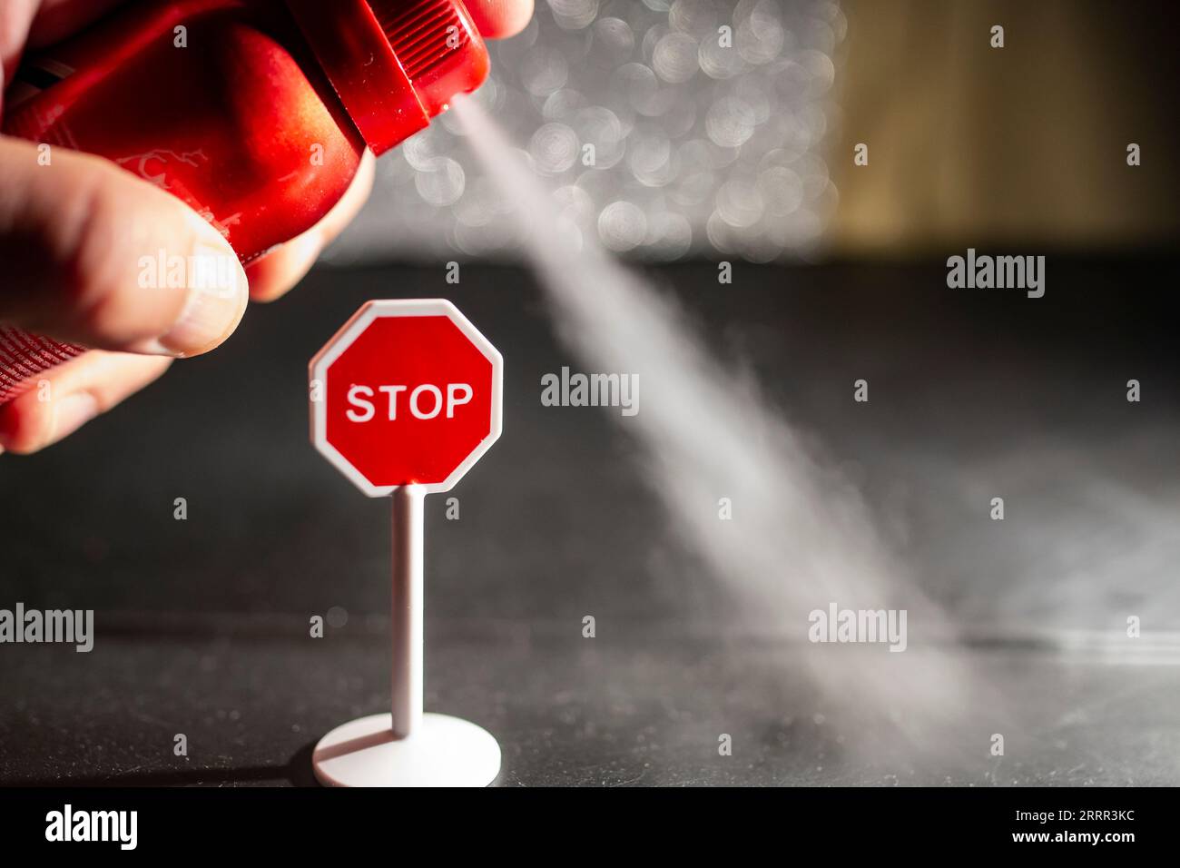 Utilisation d'un vaporisateur rouge avec du déodorant contre un panneau d'arrêt, concept de problème environnemental, mise au point douce en gros plan Banque D'Images