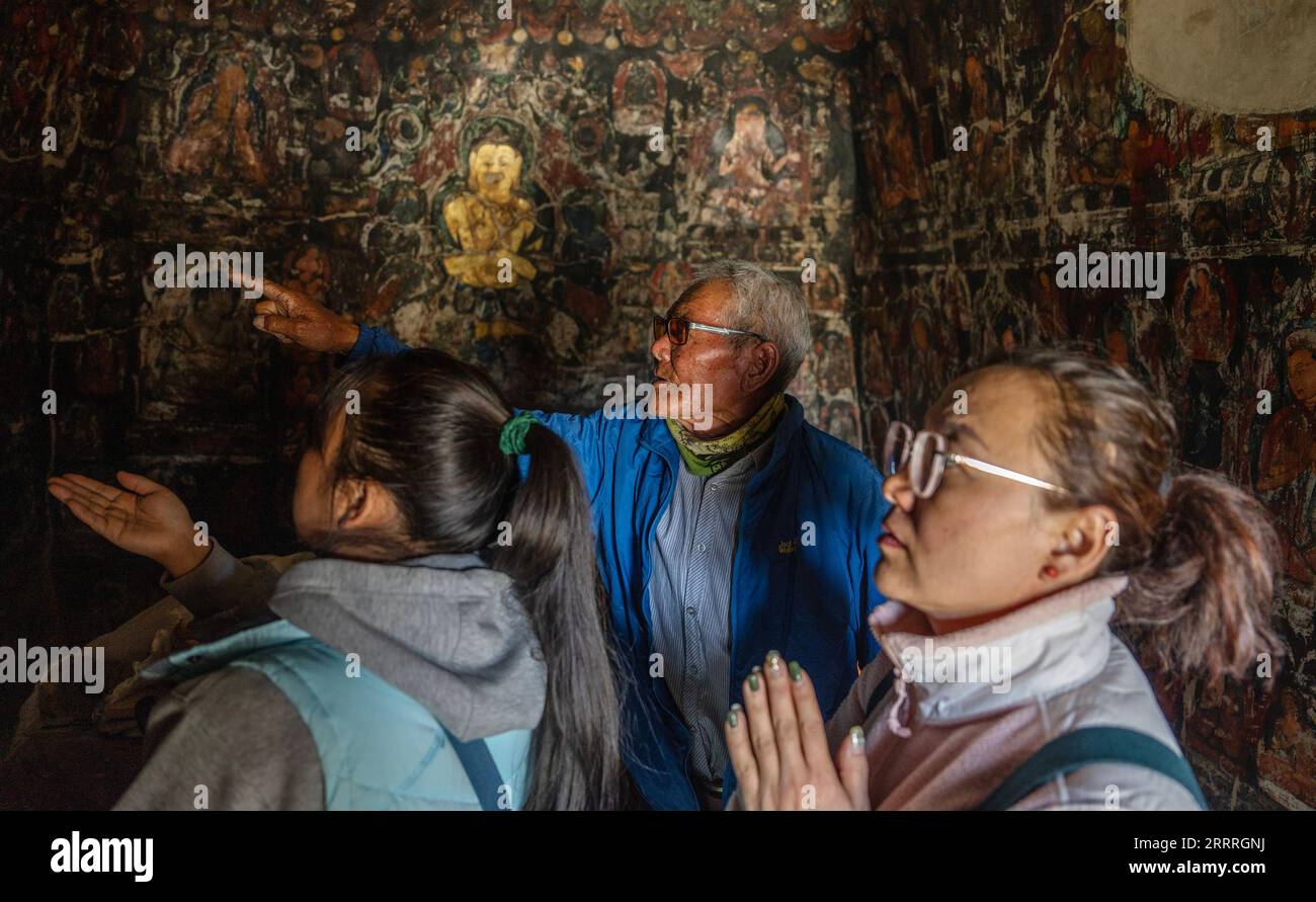 230528 -- ZANDA, 28 mai 2023 -- Rigzin Wangzhab C présente des peintures murales aux touristes dans une grotte du comté de Zanda, préfecture de Ngari, région autonome du Tibet du sud-ouest de la Chine, le 26 mai 2023. Caché parmi les collines de grès dans l'ouest reculé du Tibet, une étendue de cavernes en forme de nid d'abeille est bien au-delà de la portée de la plupart des voyageurs. Connues sous le nom de grottes de Donggar et de Piyang, les cavernes vieilles de 1 000 ans de la préfecture de Ngari de la région autonome du Tibet abritent l une des plus grandes collections de peintures murales bouddhistes tibétaines au monde. Rigzin Wangzhab, 75 ans, garde le site depuis plus de 20 ans. Quand j'étais ver Banque D'Images