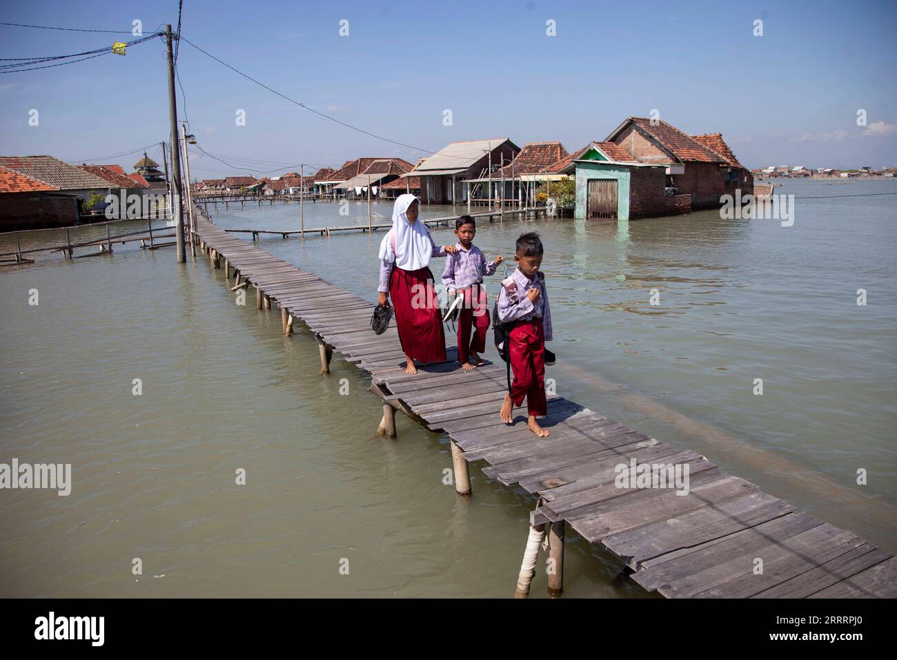 230609 -- DEMAK, le 9 juin 2023 -- des étudiants marchent sur un pont près d'un quartier résidentiel entouré d'eau dans le village de Timbulsloko à Demak, Java central, Indonésie, le 8 juin 2023. L ' élévation du niveau de la mer et l ' affaissement de la surface terrestre ont fait que certains villages étaient entourés d ' eau de mer. Photo de /Xinhua INDONESIA-DEMAK-VILLAGE QUI COULE AdityaxIrawan PUBLICATIONxNOTxINxCHN Banque D'Images