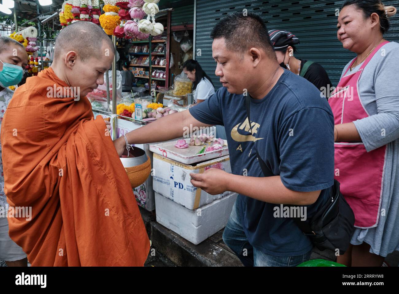 Un moine bouddhiste thaïlandais sur son aumône du matin quotidien autour de la collecte de l'aumône, (généralement de la nourriture) ; ici des vendeurs de rue à Silom Road, Bangkok, Thaïlande Banque D'Images