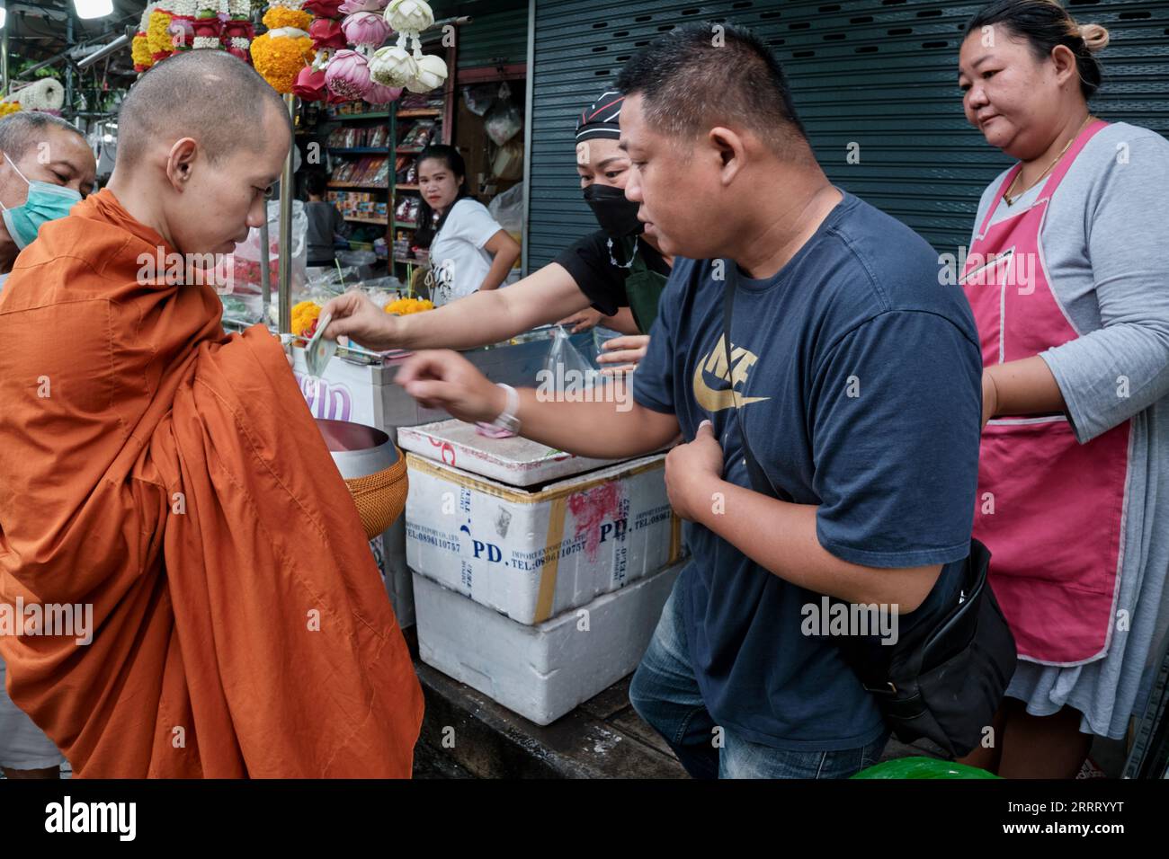 Un moine bouddhiste thaïlandais sur son aumône du matin quotidien autour de la collecte de l'aumône, (généralement de la nourriture) ; ici des vendeurs de rue à Silom Road, Bangkok, Thaïlande Banque D'Images