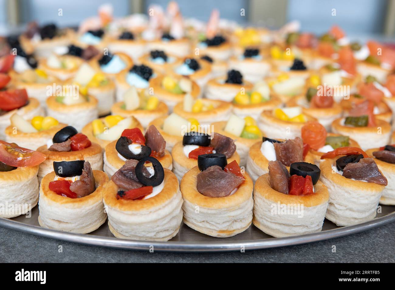 Grande assiette remplie de canapés méditerranéens avec un accent particulier sur de savoureuses pâtisseries vol-au-vent fourrées d'anchois et d'olives noires Banque D'Images