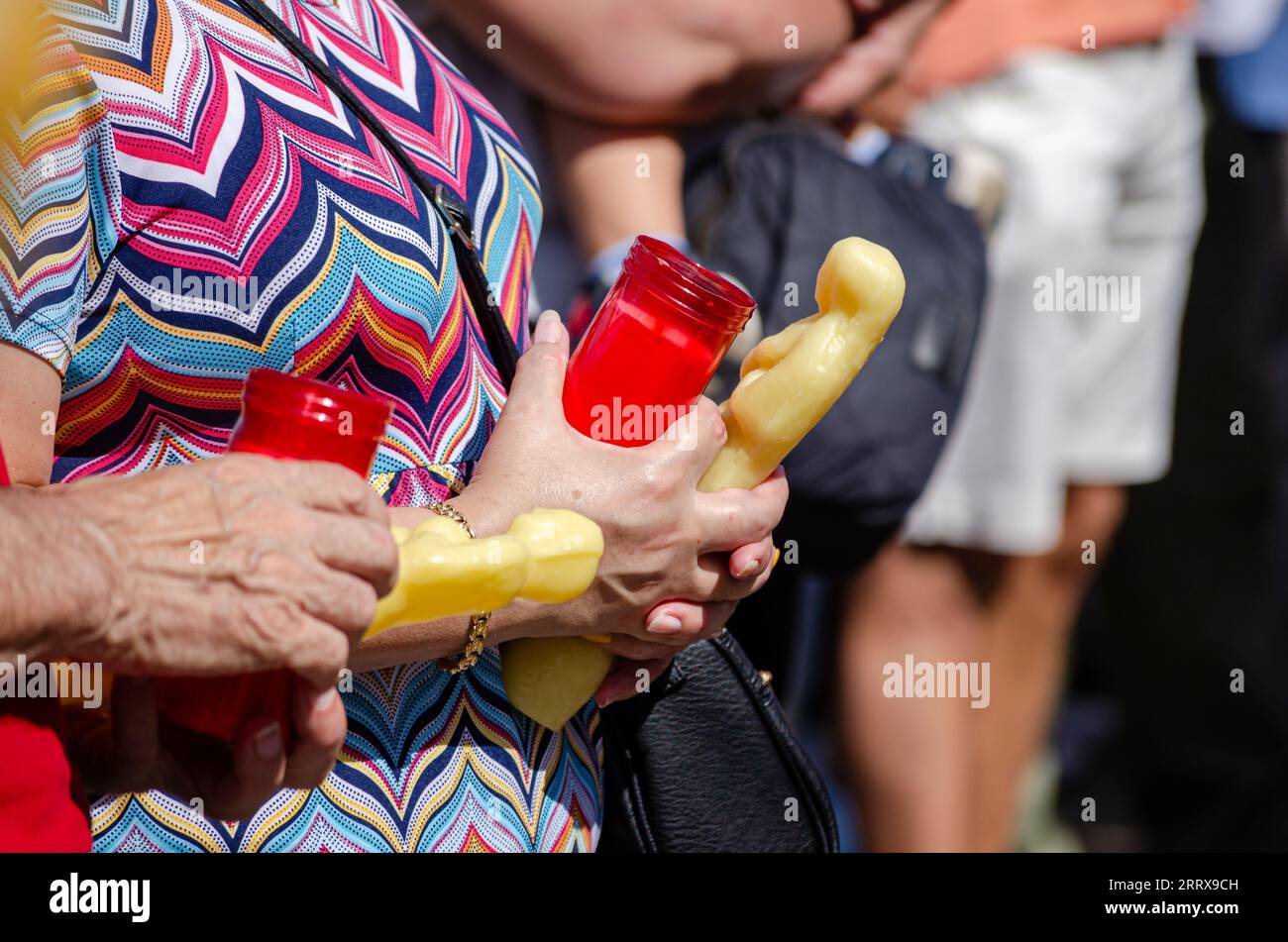 Concentration sélective, mains de personnes tenant des offrandes votives et bougies de cire lors d'un événement religieux catholique Banque D'Images