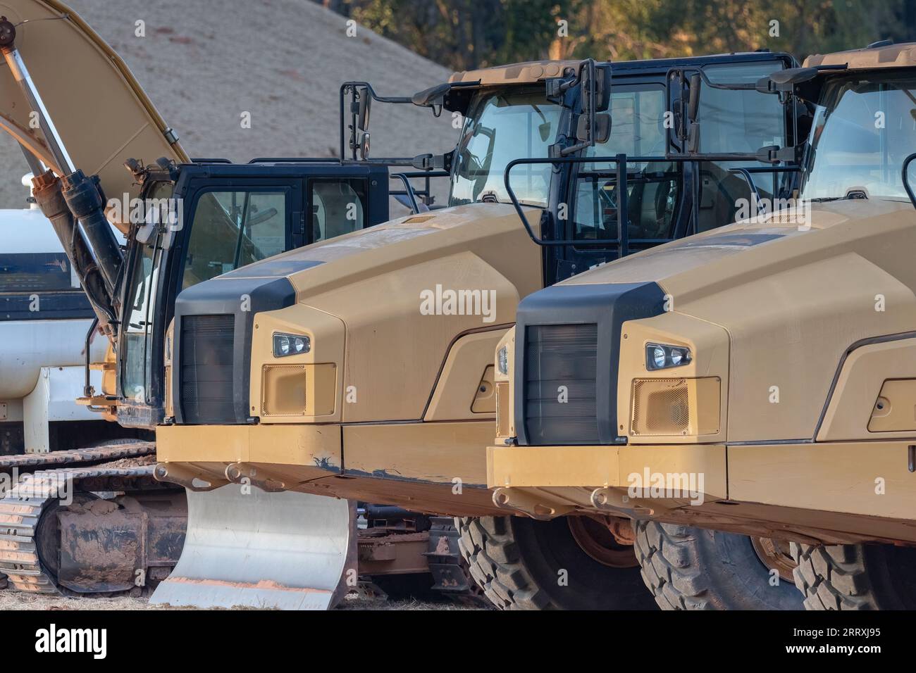 Camions lourds et équipement sur un chantier de construction près d'un quartier résidentiel. Banque D'Images
