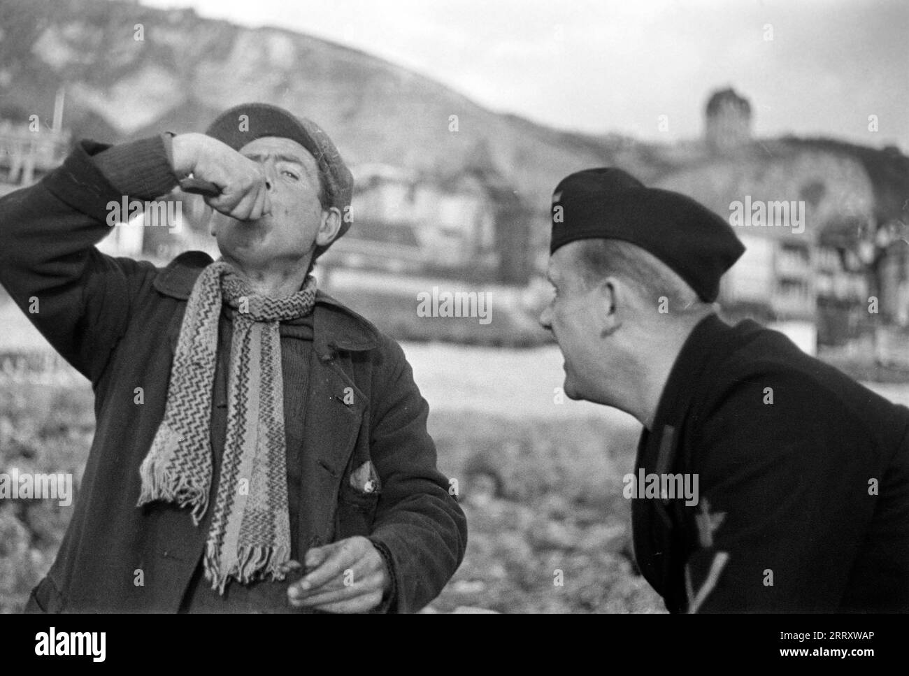 Ein Muschelernter am Strand von le Havre zeigt dem Fotografen Erich Andres in der Uniform der Kriegsmarine, wie man Muscheln erntet, öffnet und isst, 1940. Une récolteuse de moules sur la plage du Havre montre au photographe Erich Andres dans son uniforme de Kriegsmarine comment récolter, ouvrir et manger des moules, 1940. Banque D'Images