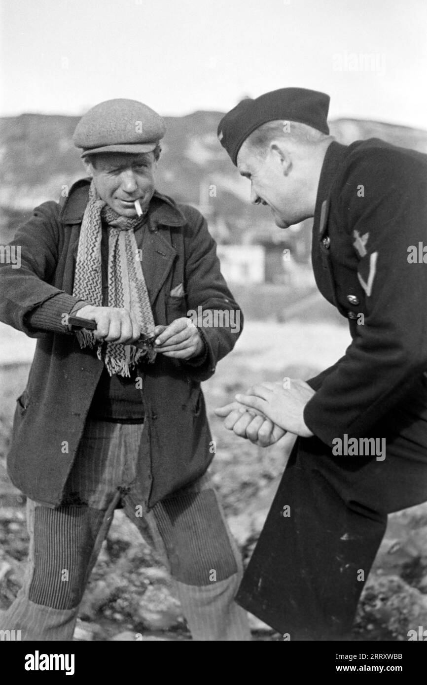Ein Muschelernter am Strand von le Havre zeigt dem Fotografen Erich Andres in der Uniform der Kriegsmarine, wie man Muscheln erntet, öffnet und isst, 1940. Une récolteuse de moules sur la plage du Havre montre au photographe Erich Andres dans son uniforme de Kriegsmarine comment récolter, ouvrir et manger des moules, 1940. Banque D'Images