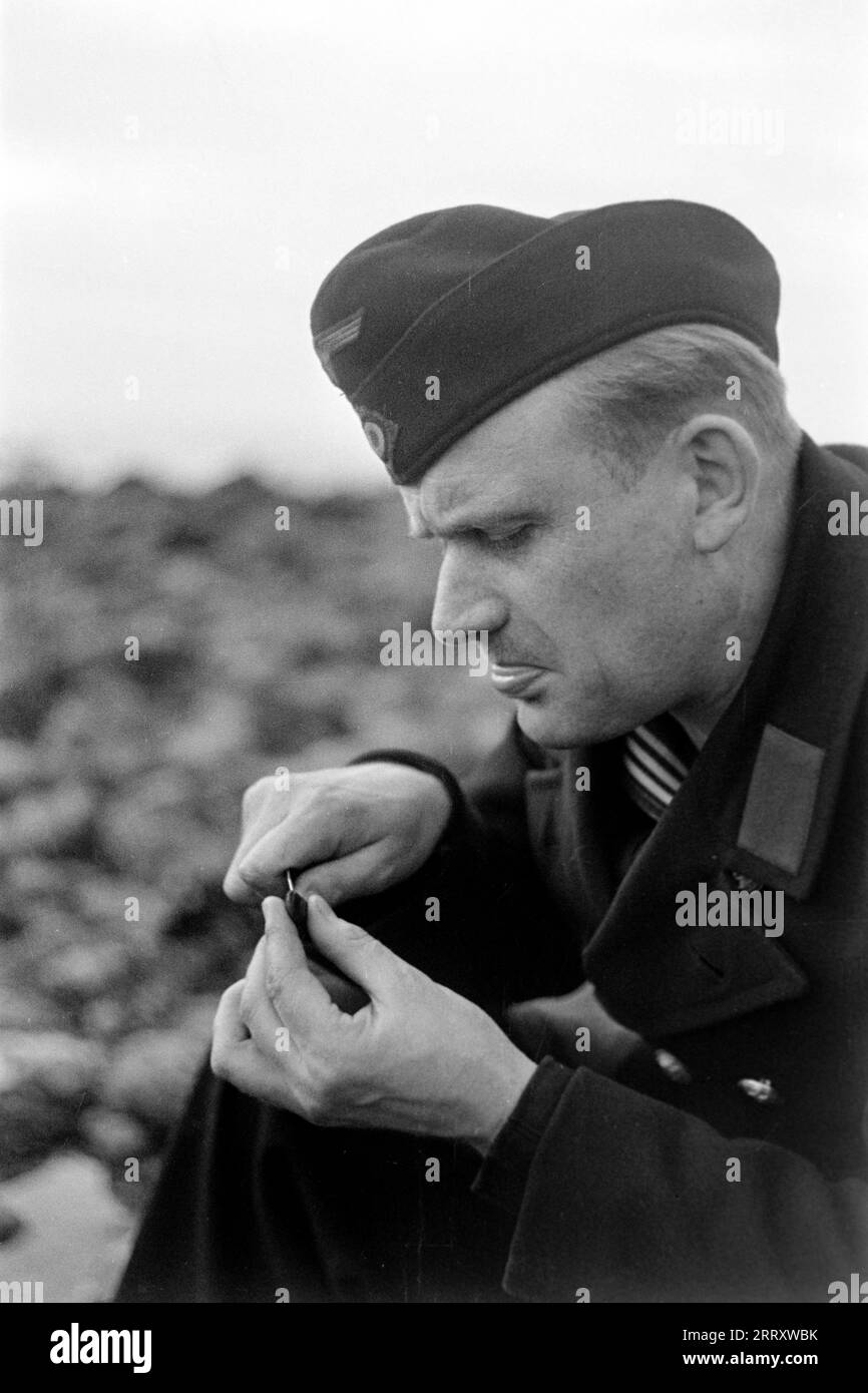 Der Fotograf Erich Andres in der Uniform der Kriegsmarine öffnet Muscheln am Strand von le Havre UM sie zu verzehren, 1940. Le photographe Erich Andres dans son uniforme de Kriegsmarine ouvre des moules sur la plage du Havre pour les manger, 1940. Banque D'Images