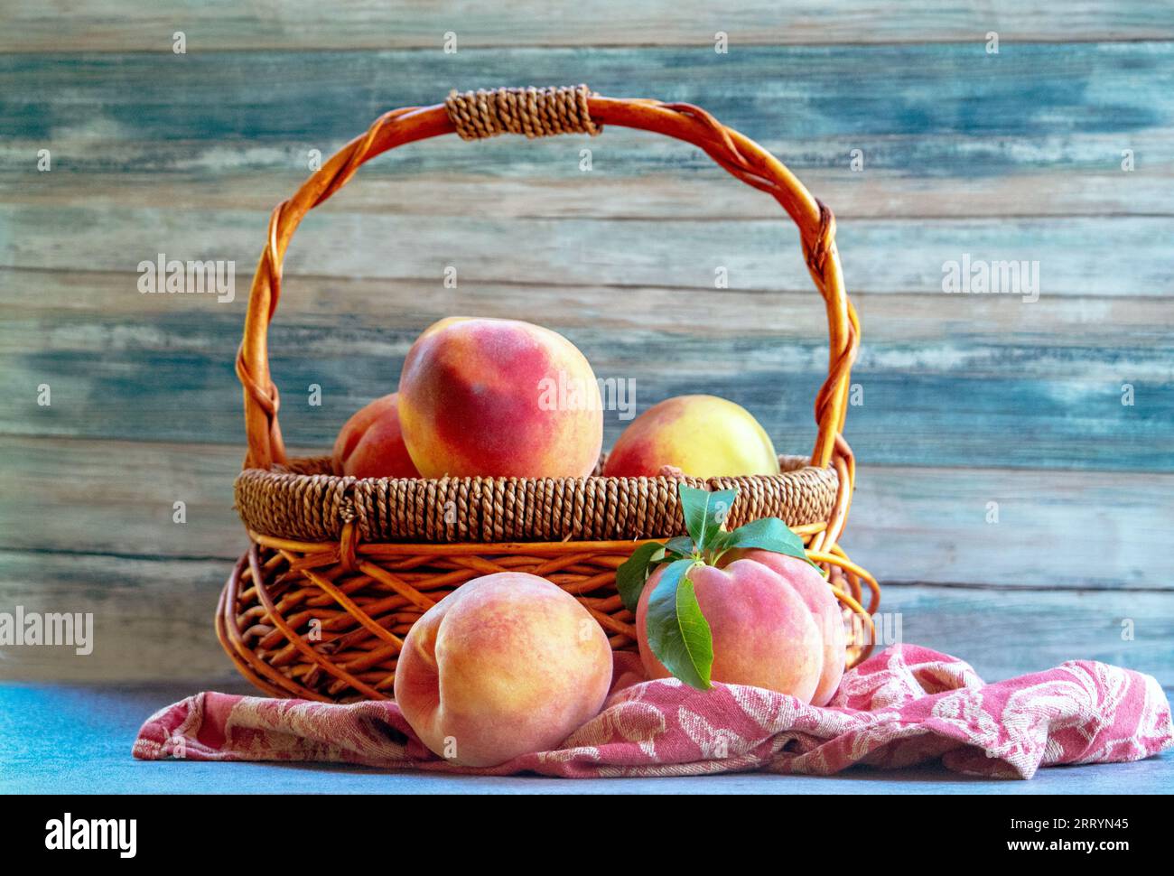 Le panier rustique en osier contient des pêches fraîches et juteuses Banque D'Images
