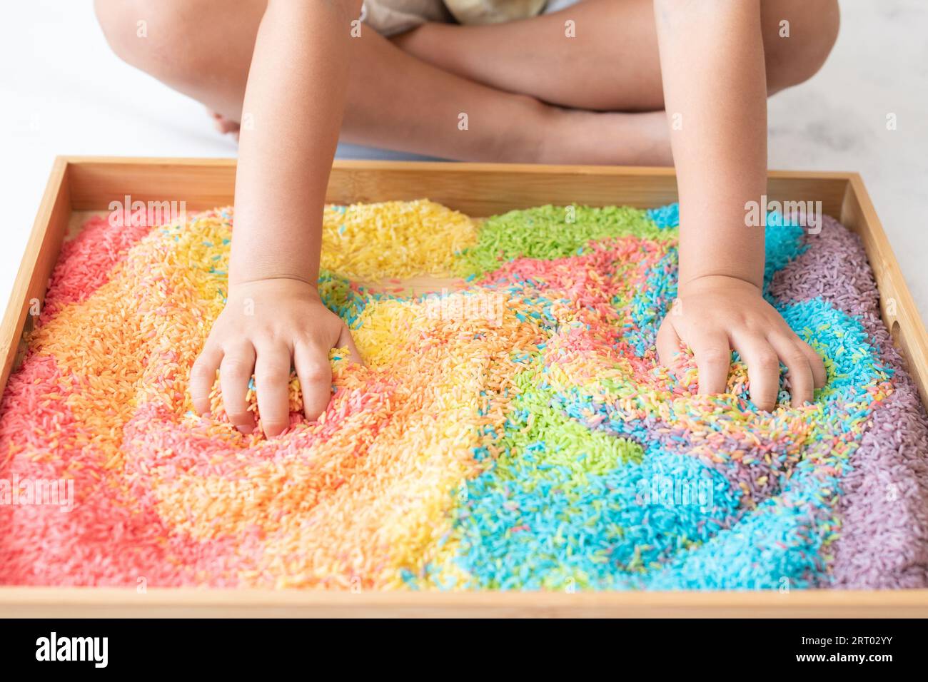 Les mains des enfants dans un bac à riz sensoriel Banque D'Images