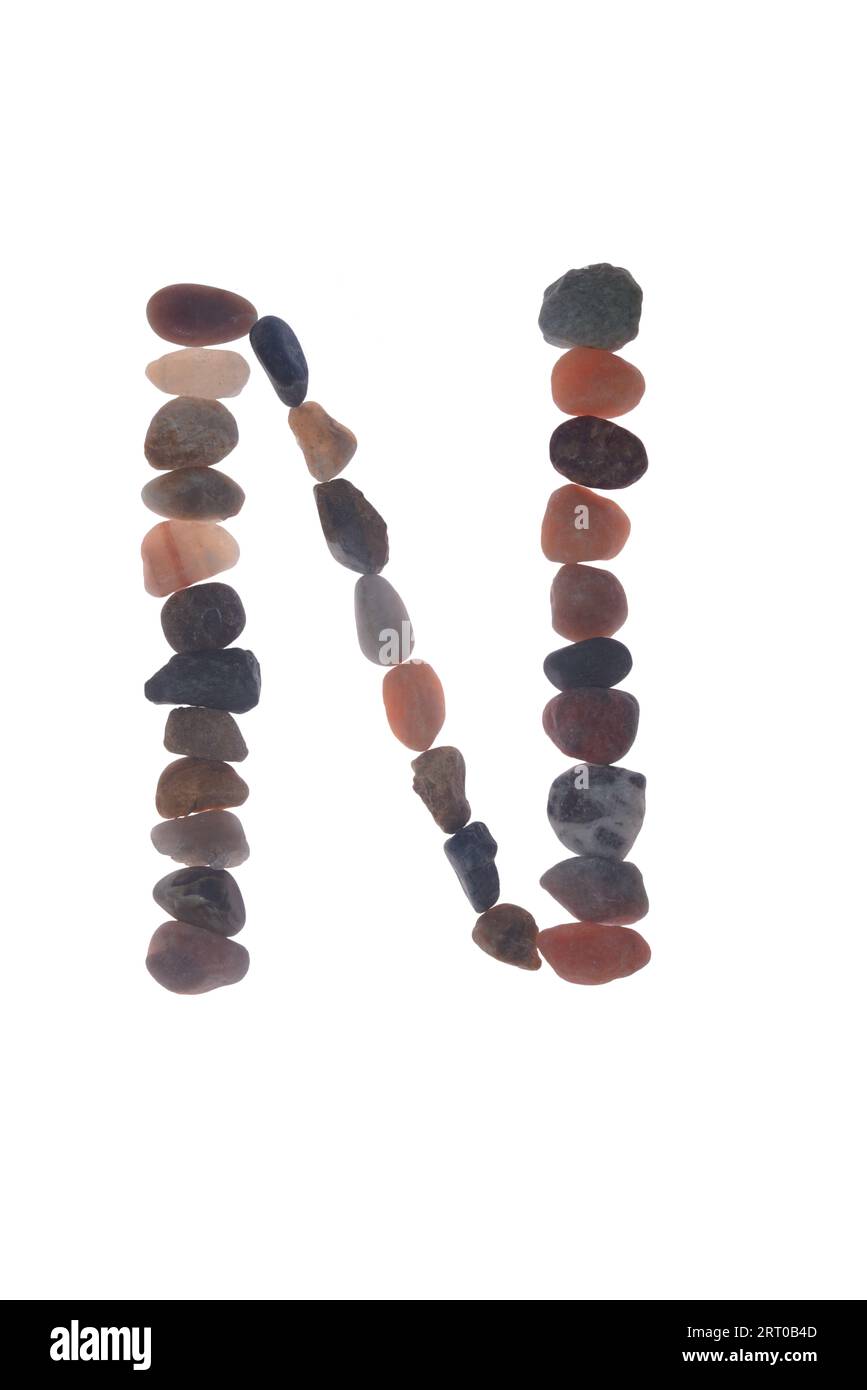 Lettre N fabriquée à la main à l'aide de petites pierres ou cailloux, objet unique. créer un impact artistique signifiant à votre message, sur fond blanc. Banque D'Images