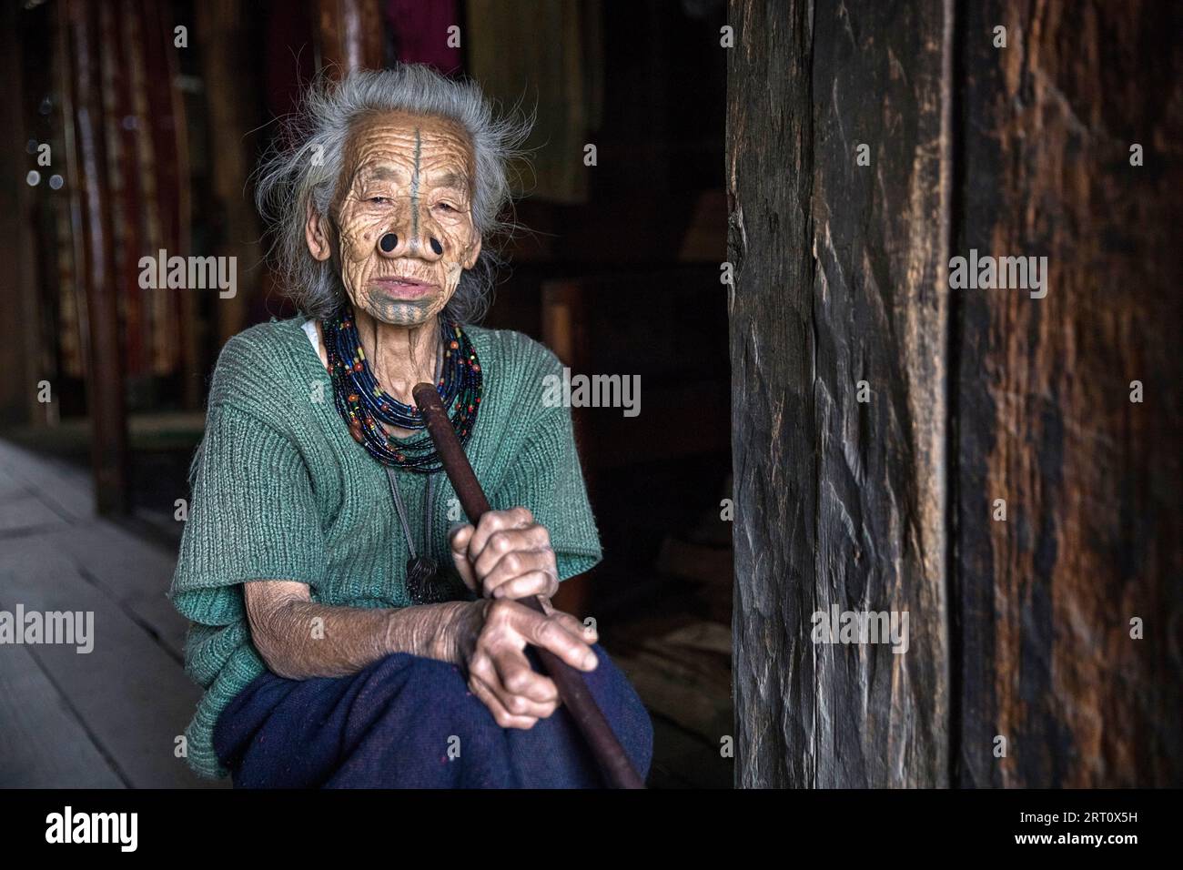 Femme de la tribu apatani dans une maison d'un petit village près de Ziro, avec des tatouages faciaux traditionnels et des bouchons de nez traditionnels, Ziro, Inde Banque D'Images