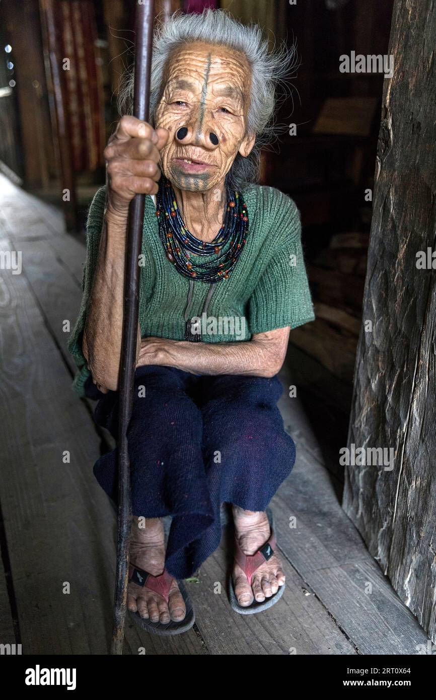 Femme de la tribu apatani dans une maison d'un petit village près de Ziro, avec des tatouages faciaux traditionnels et des bouchons de nez traditionnels, Ziro, Inde Banque D'Images