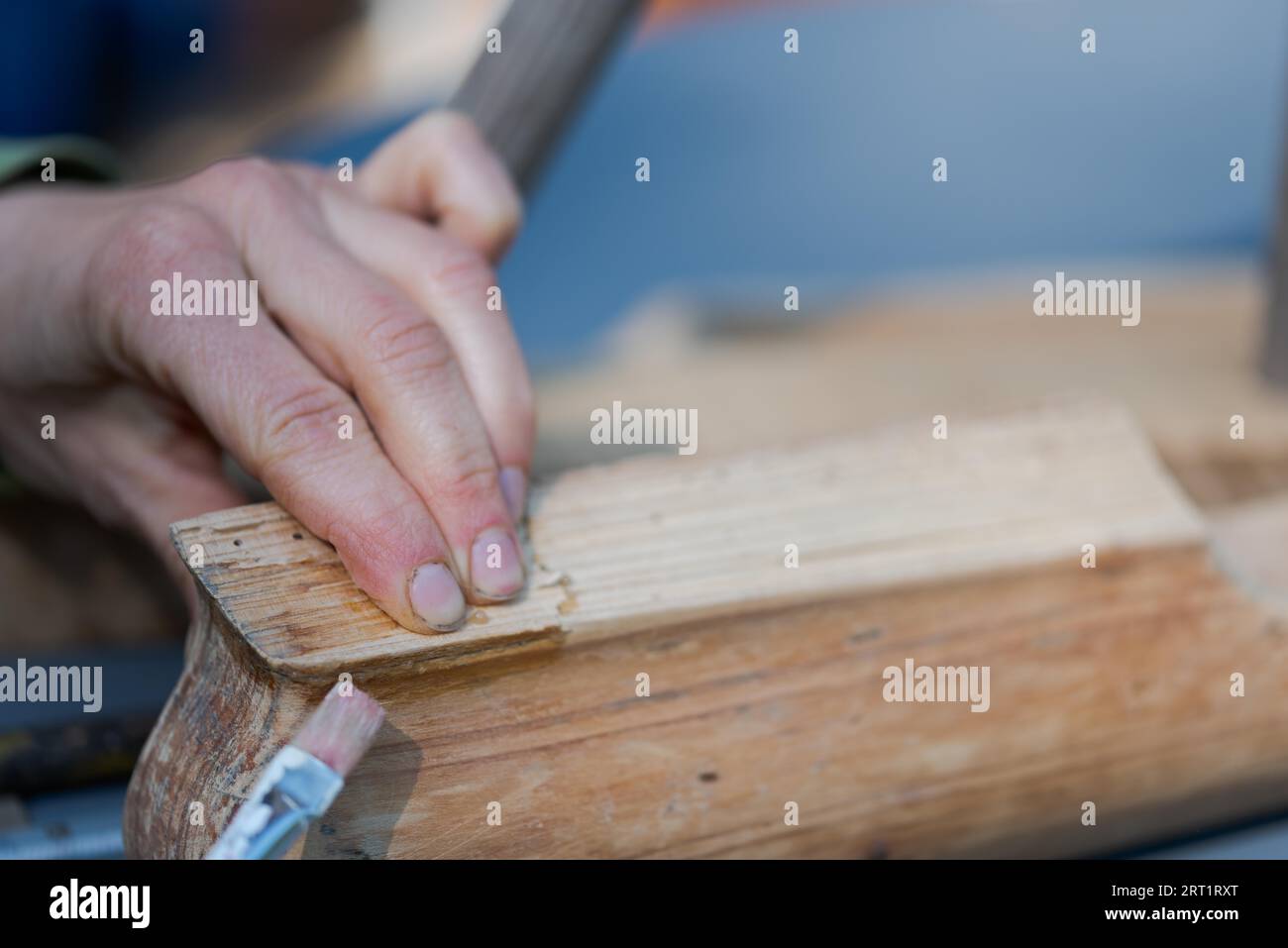 Mains humaines application de colle d'os avec la brosse sur un morceau de vieux mobilier en bois Banque D'Images