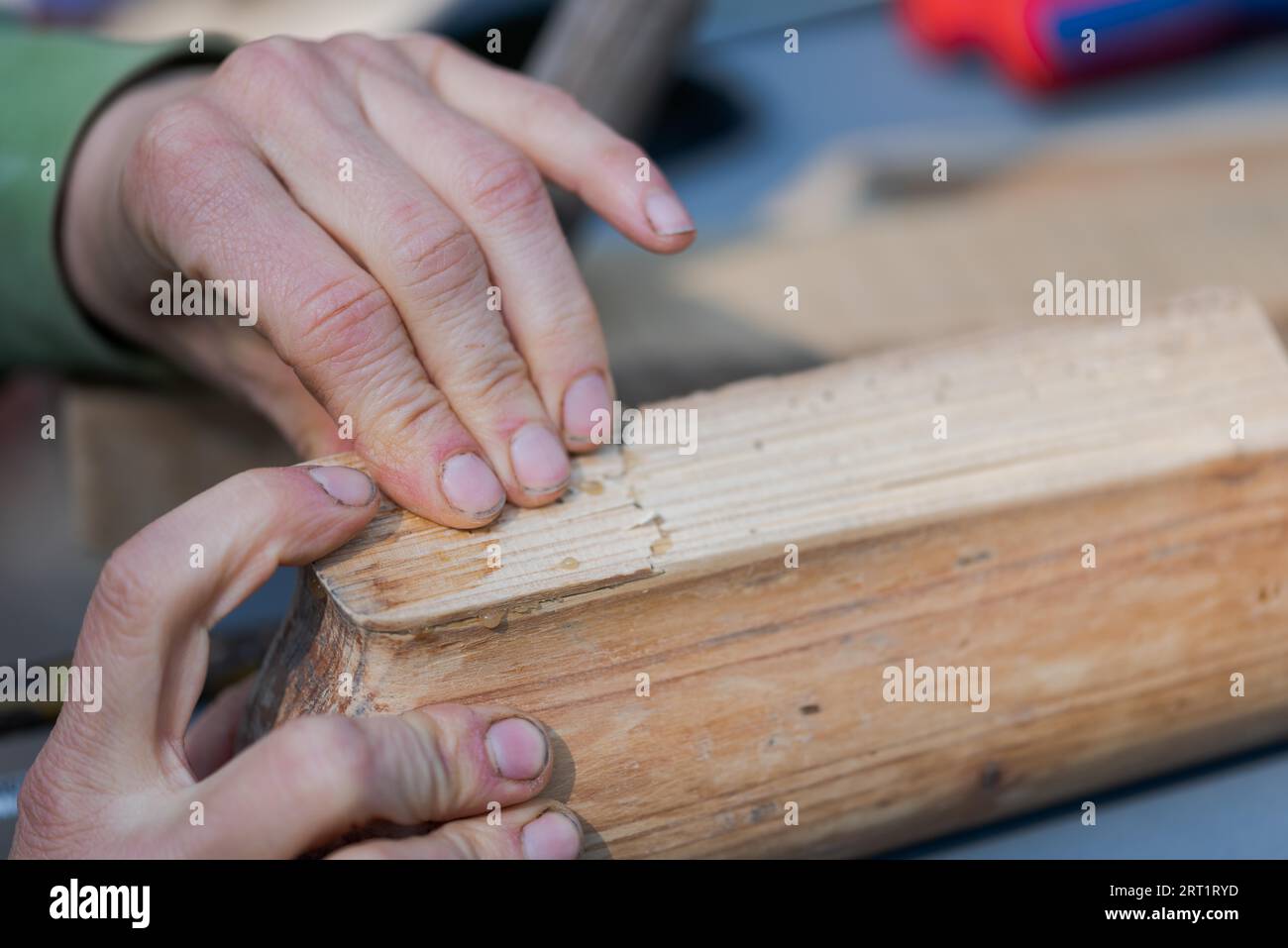 Mains humaines appuyant sur deux pièces de vieux meubles en bois qui ont été collées avec de la colle d'os Banque D'Images