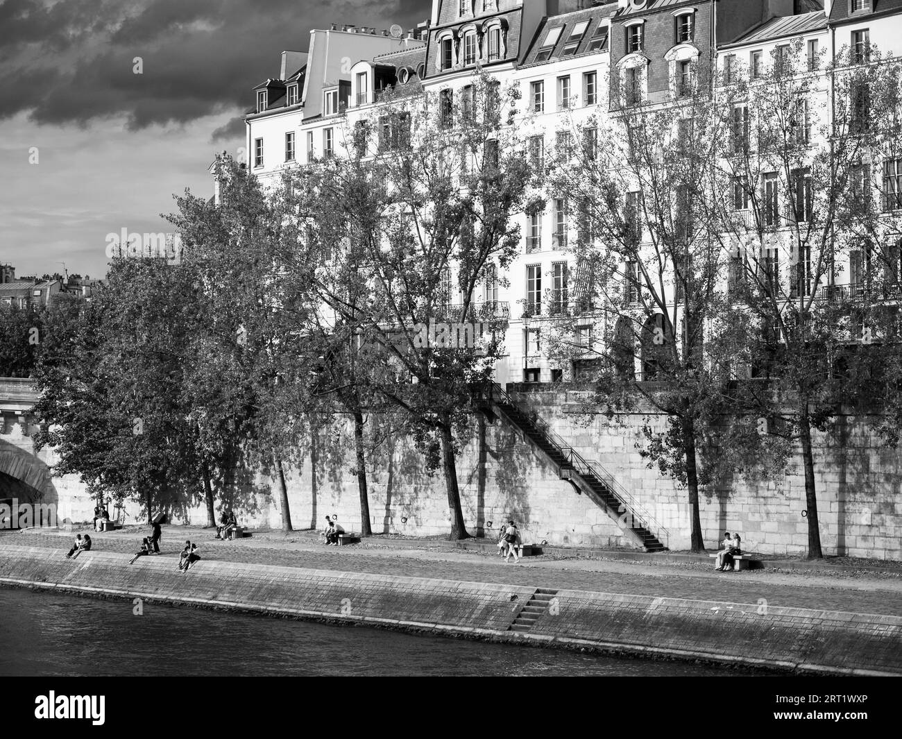 Noir et blanc, les gens se détendant sur la rive de la Seine, Île Saint-Louis, île en Seine, Paris, France, Europe, UE. Banque D'Images