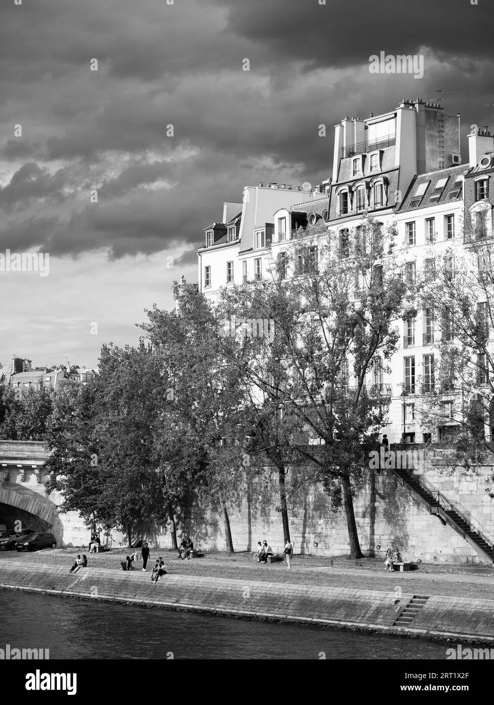Noir et blanc, les gens se détendant sur la rive de la Seine, Île Saint-Louis, île en Seine, Paris, France, Europe, UE. Banque D'Images