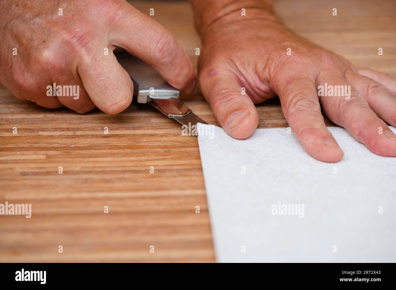 Les travailleurs préparent le papier peint pour l'accrocher. Mesurer un rouleau de papier peint, couper le papier peint. Banque D'Images